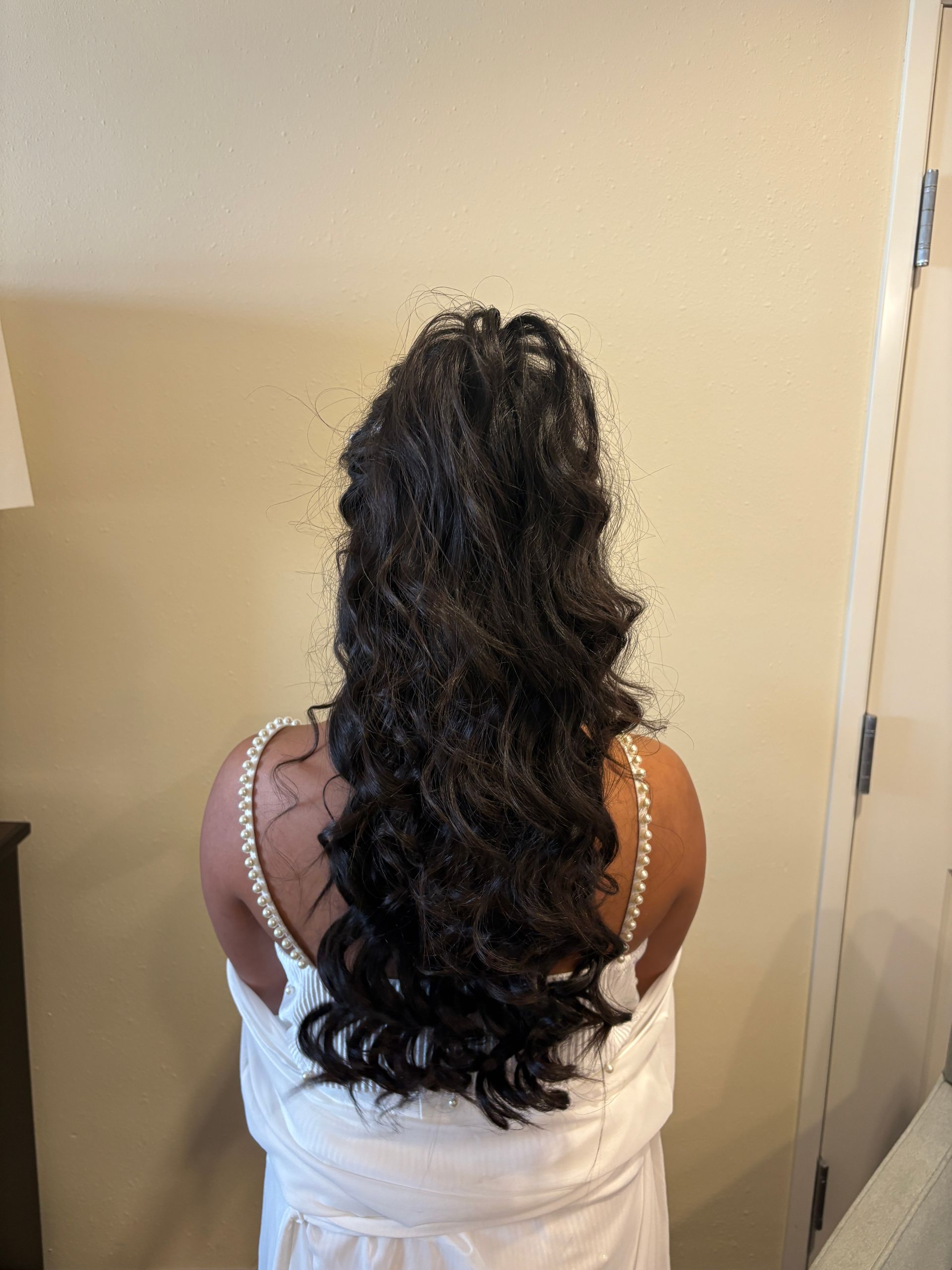 Woman with blonde updo hairstyle, wearing a black shirt with colorful flip-flops, standing in a room.