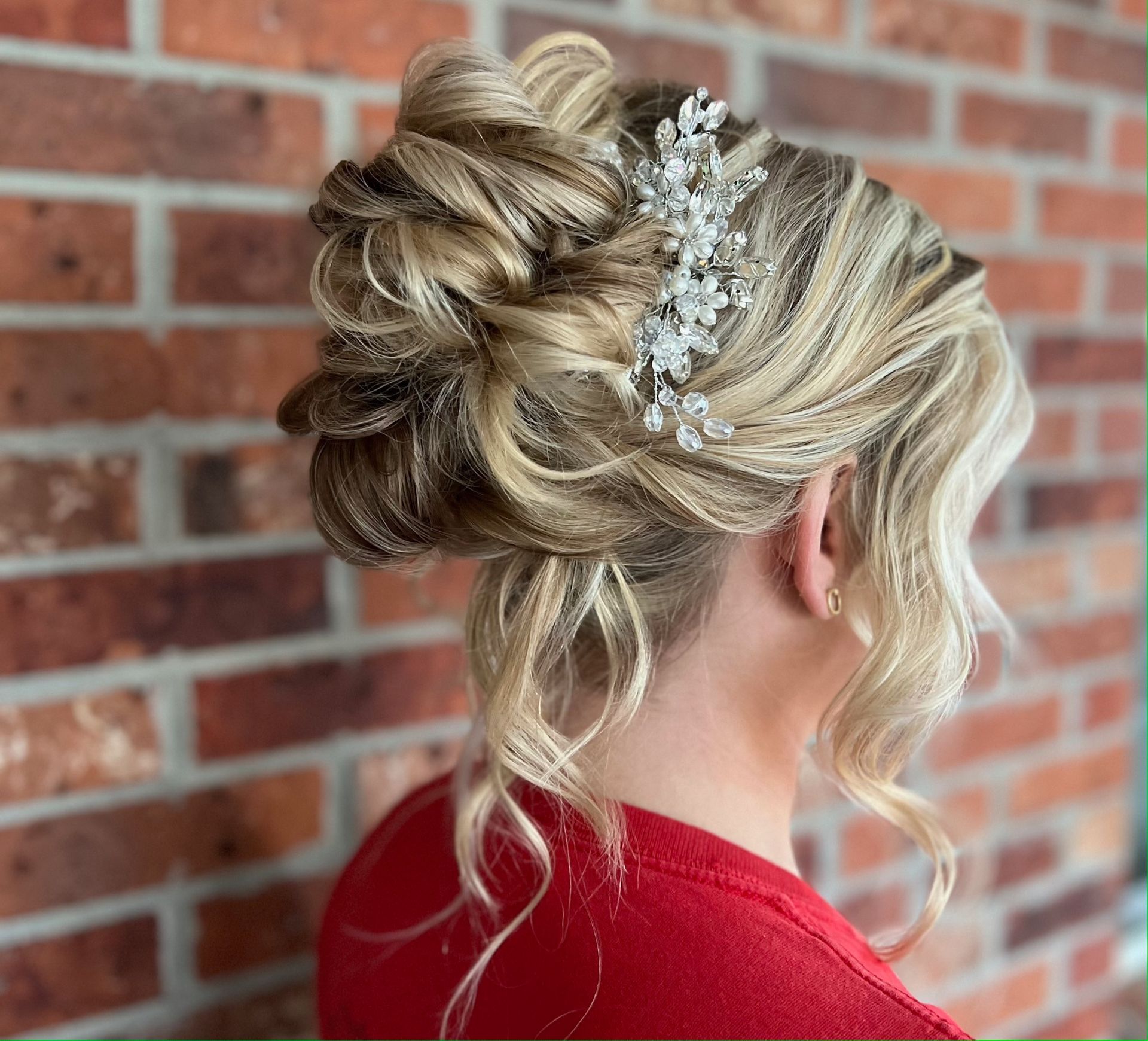 Woman with blonde updo hairstyle in front of a wooden door.