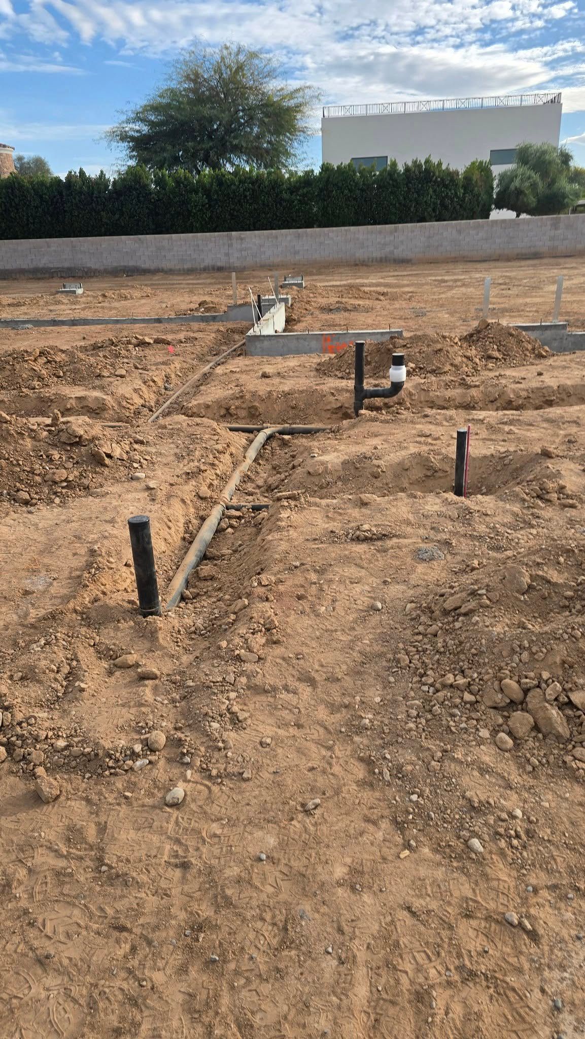A dirt field with a fence and a building in the background.