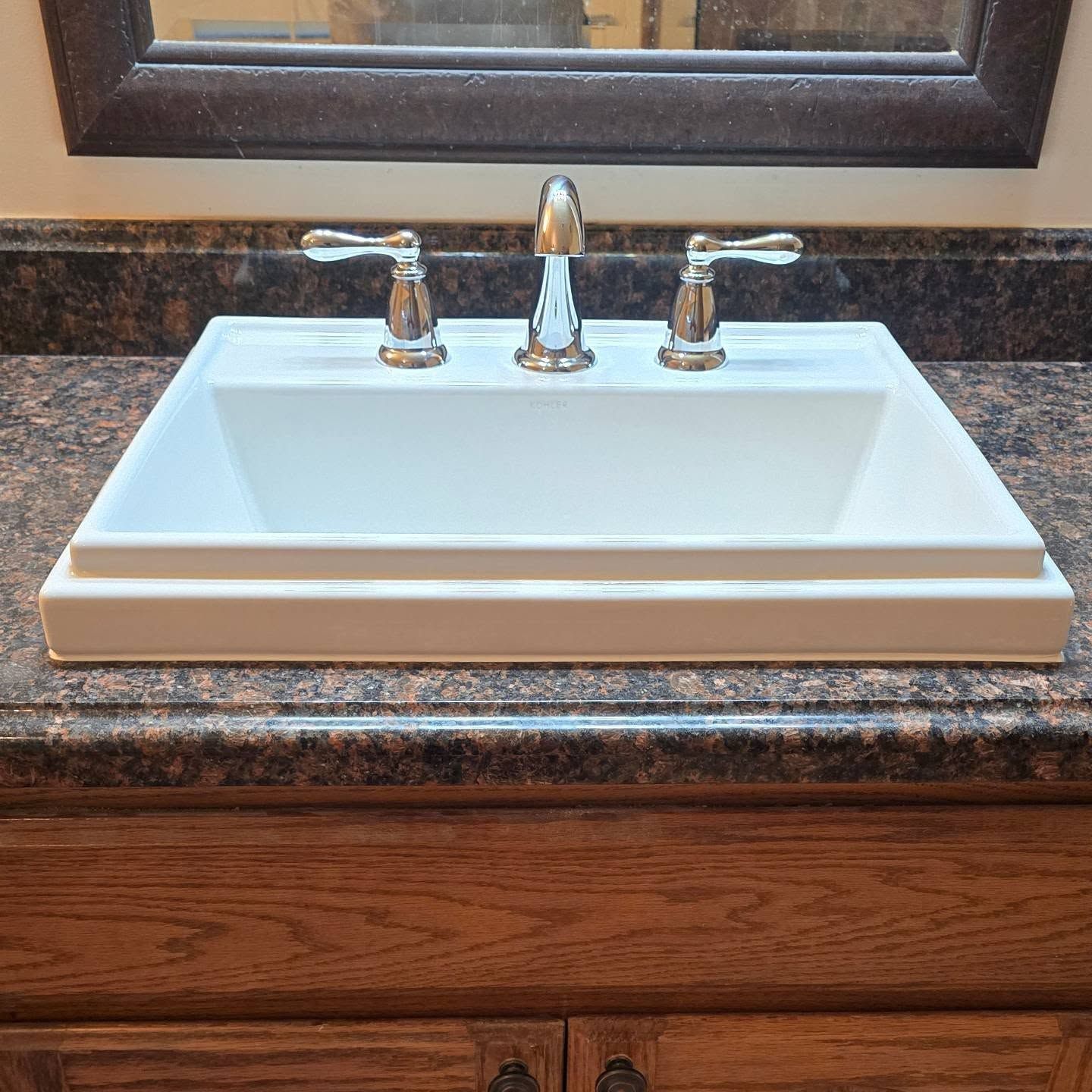 A bathroom sink is sitting on top of a granite counter.
