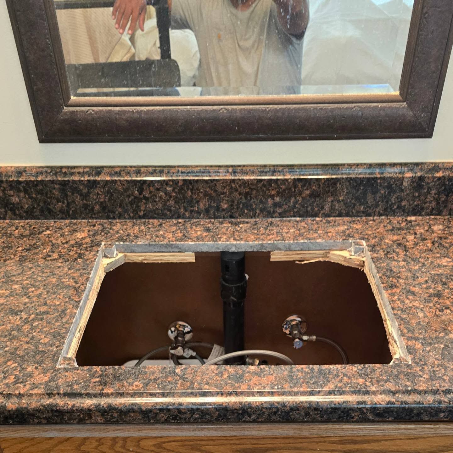 A man is taking a picture of himself in a bathroom sink