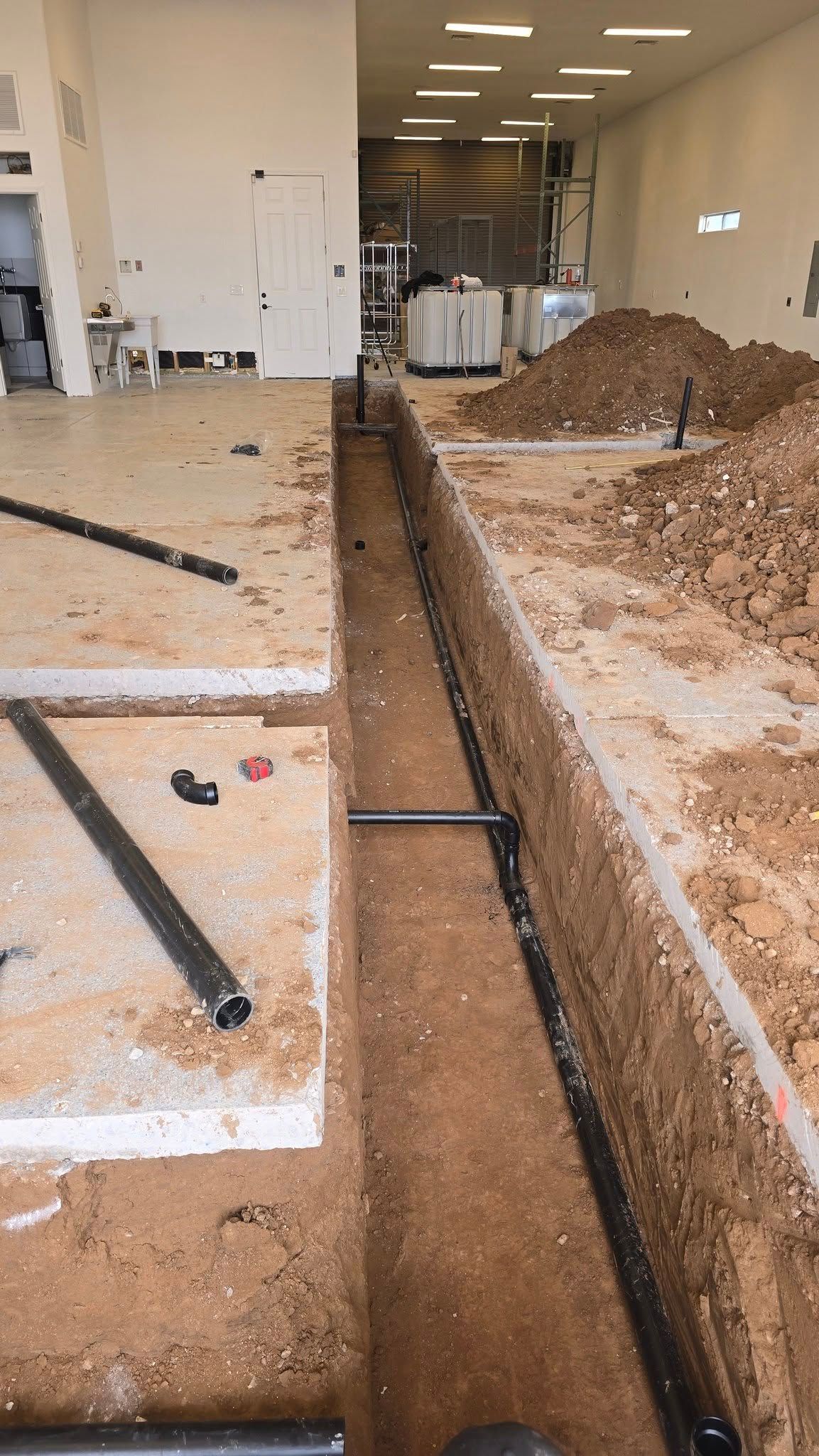 A large room with a lot of dirt and pipes in it.