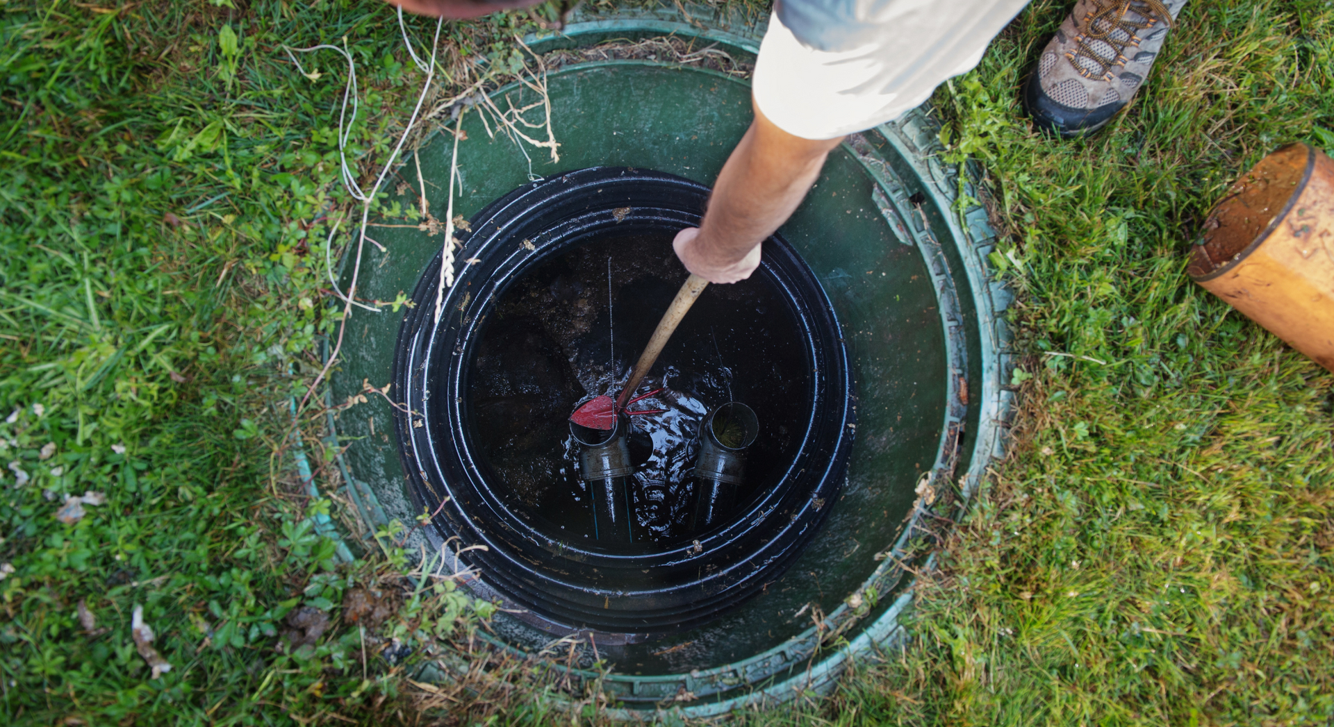 A person is using a plunger to clean a septic tank.