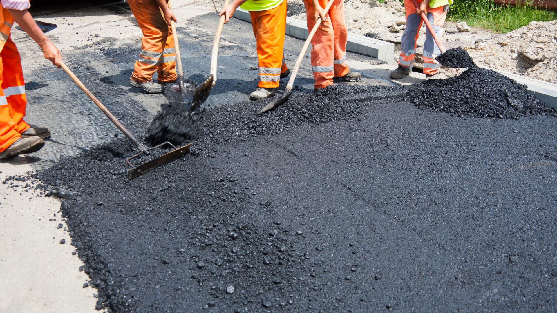 A man is spreading concrete on a sidewalk with a trowel.
