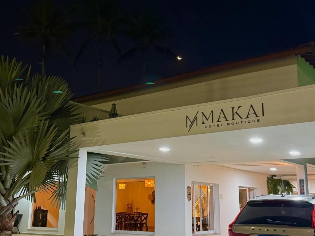Entrada do restaurante Makai à noite, com luzes aconchegantes e um carro estacionado sob um toldo creme.