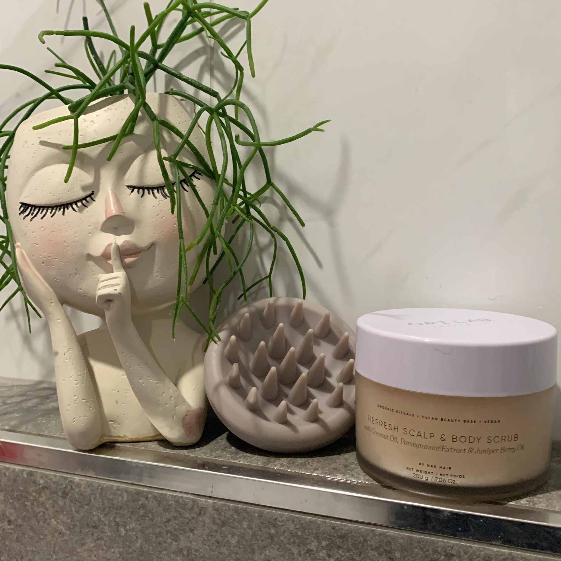 A Jar of Cream is Sitting on a Shelf Next to a Statue of a Woman — Embellish Hair and Beauty In Slade Point, QLD