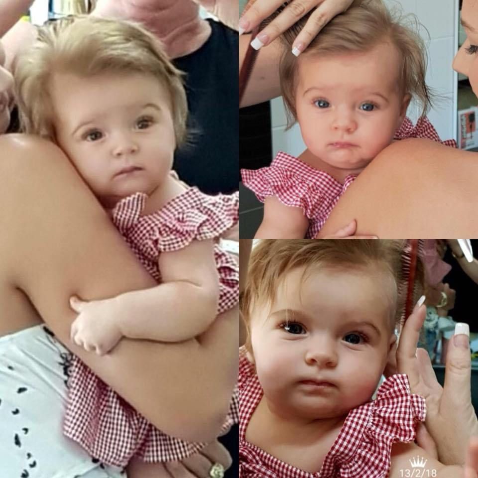 A Baby Girl in a Red and White Dress is Being Held by a Woman — Embellish Hair and Beauty In Slade Point, QLD