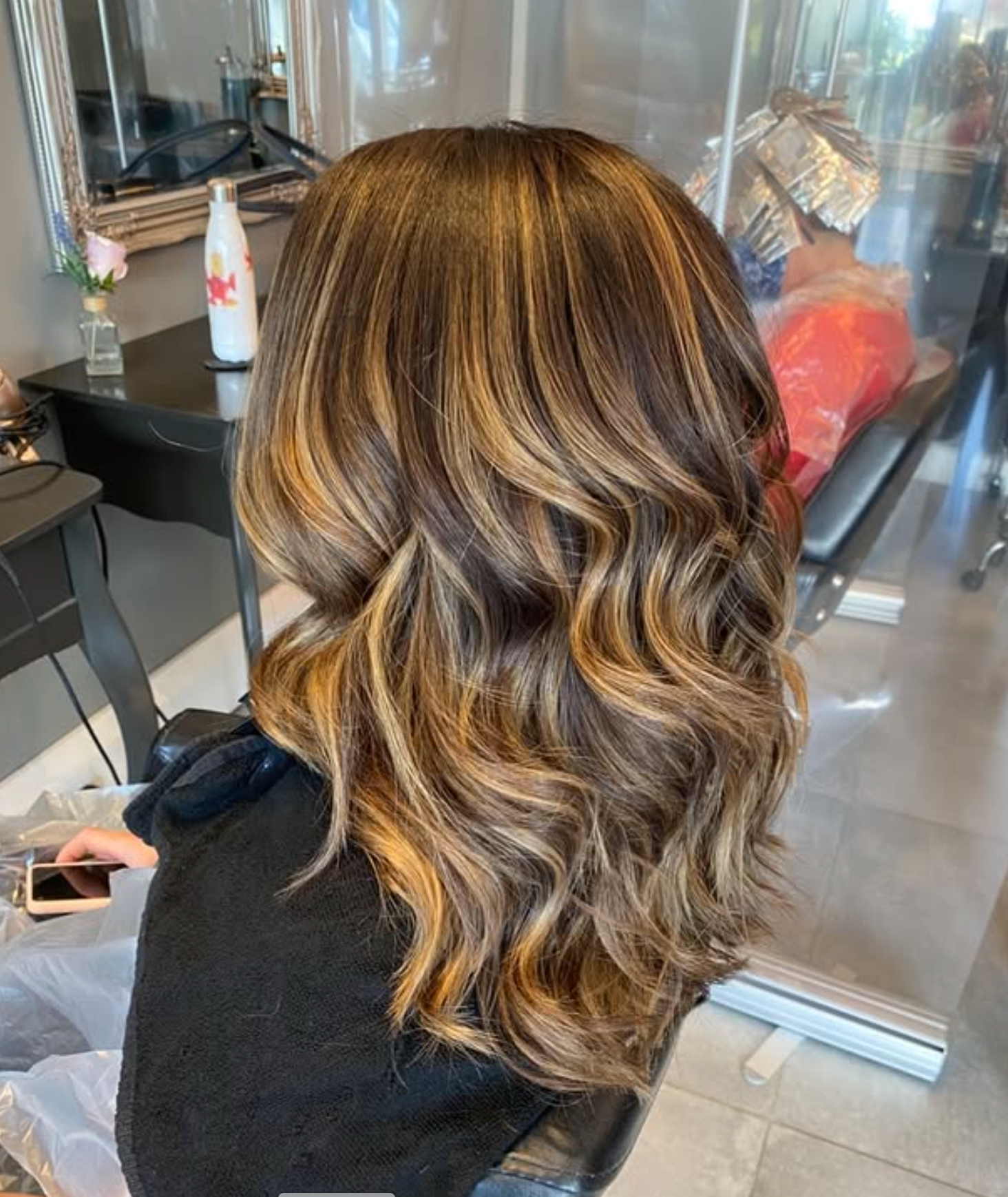 A Woman is Getting Her Hair Blow Dried by a Hairdresser in a Salon — Embellish Hair and Beauty In Slade Point, QLD