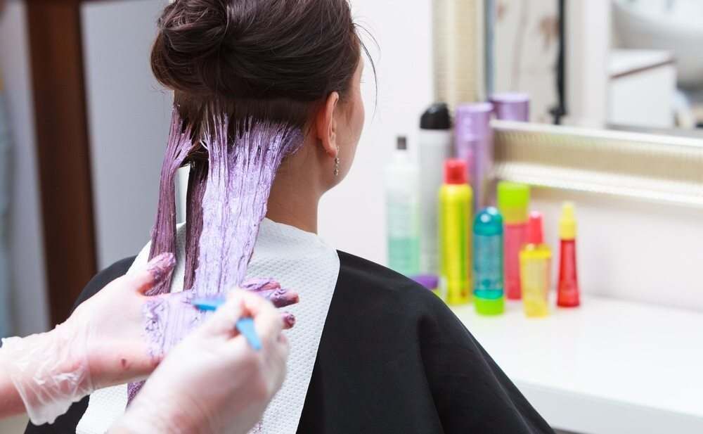 A Woman is Getting Her Hair Dyed in a Salon — Embellish Hair and Beauty In Slade Point, QLD