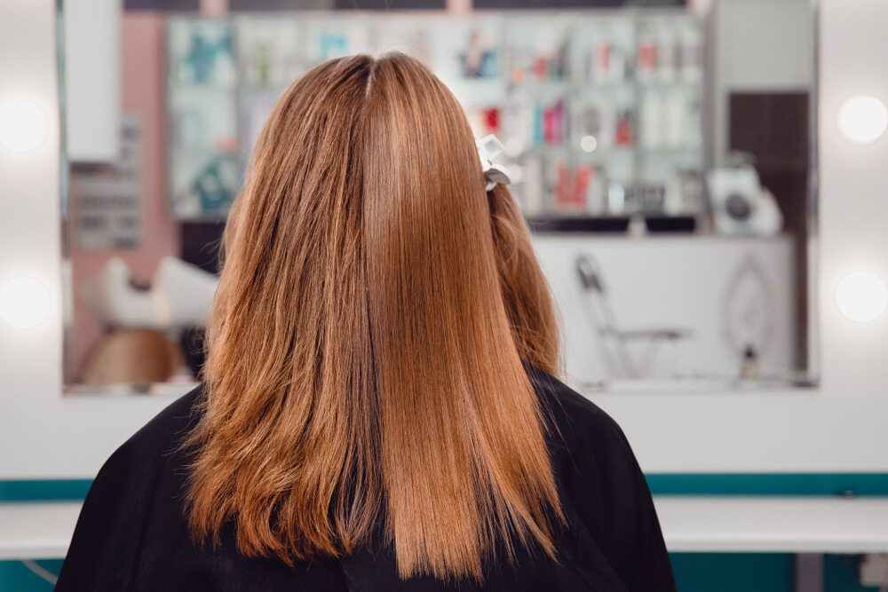 A Woman is Getting Her Hair Cut in a Salon — Embellish Hair and Beauty In Slade Point, QLD