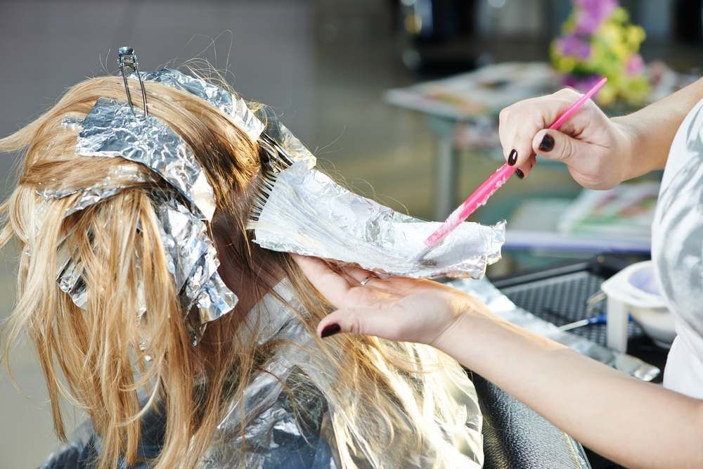 A Woman is Getting Her Hair Dyed in a Salon — Embellish Hair and Beauty In Slade Point, QLD