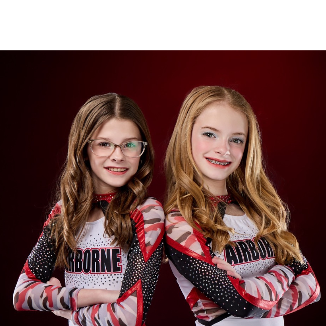 Two young girls are standing next to each other with their arms crossed.