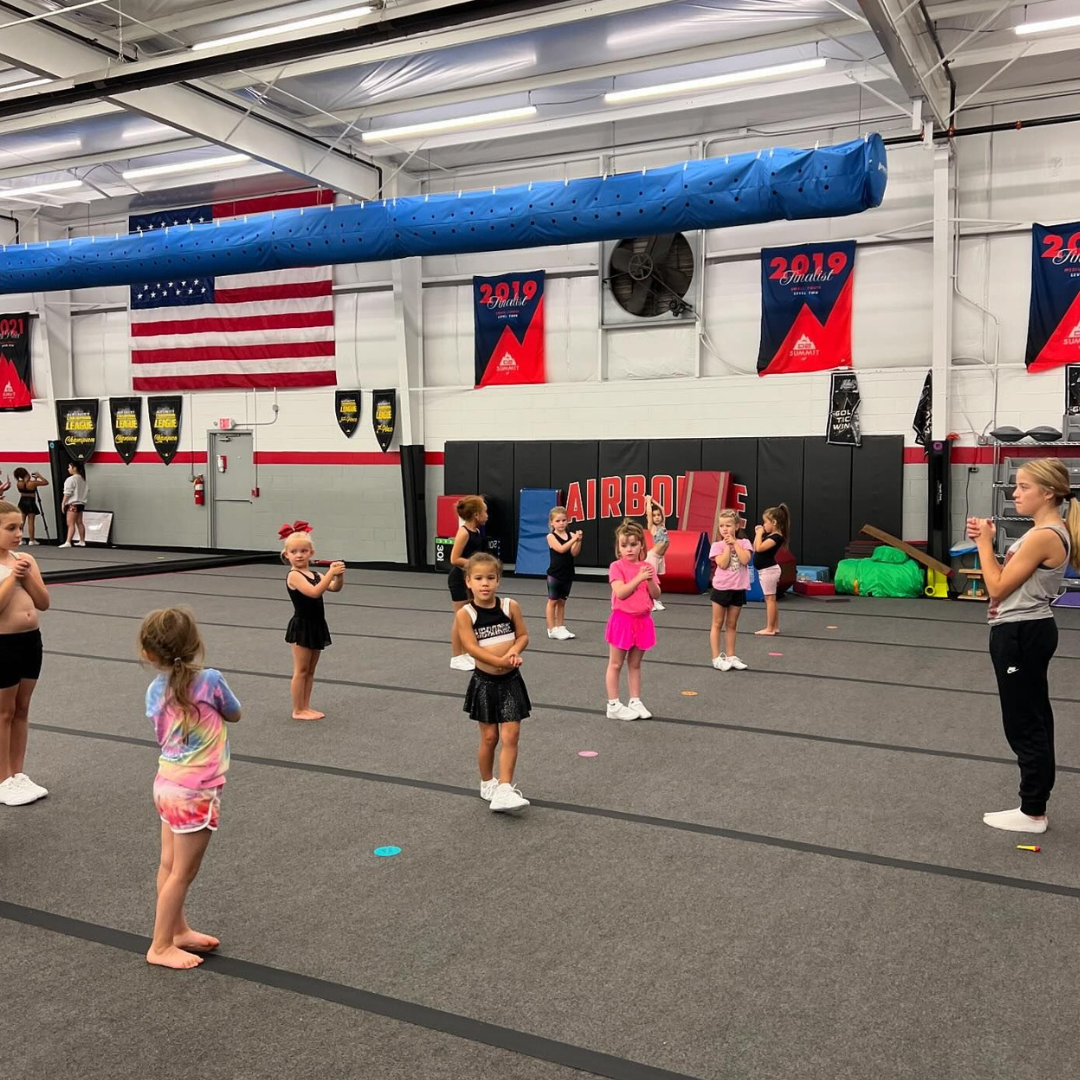 A group of young girls are standing on a gym floor