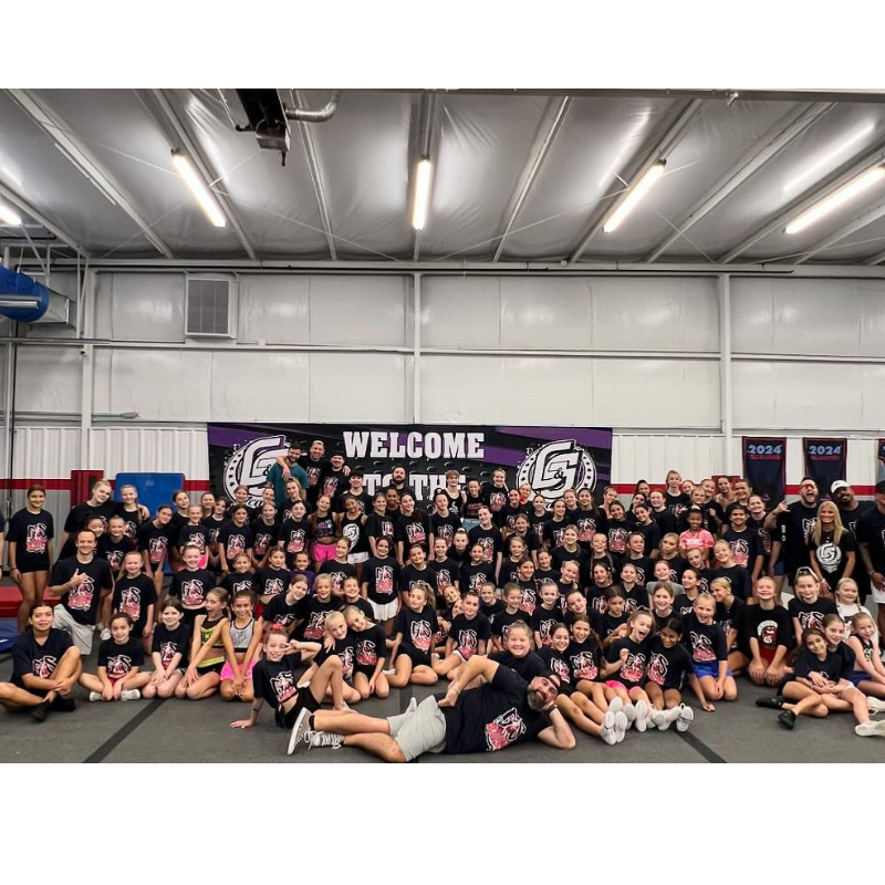 A large group of people are posing for a picture in a gym.