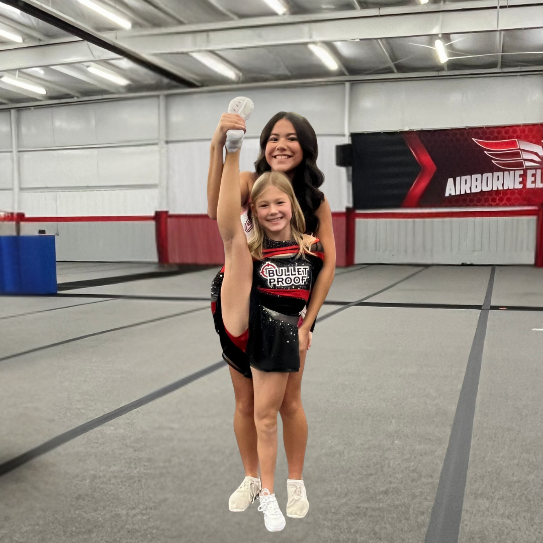 Two cheerleaders are posing for a picture in front of a sign that says airborne