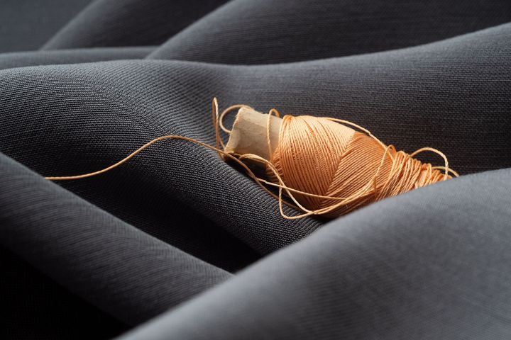 A close up of a spool of thread on a black cloth