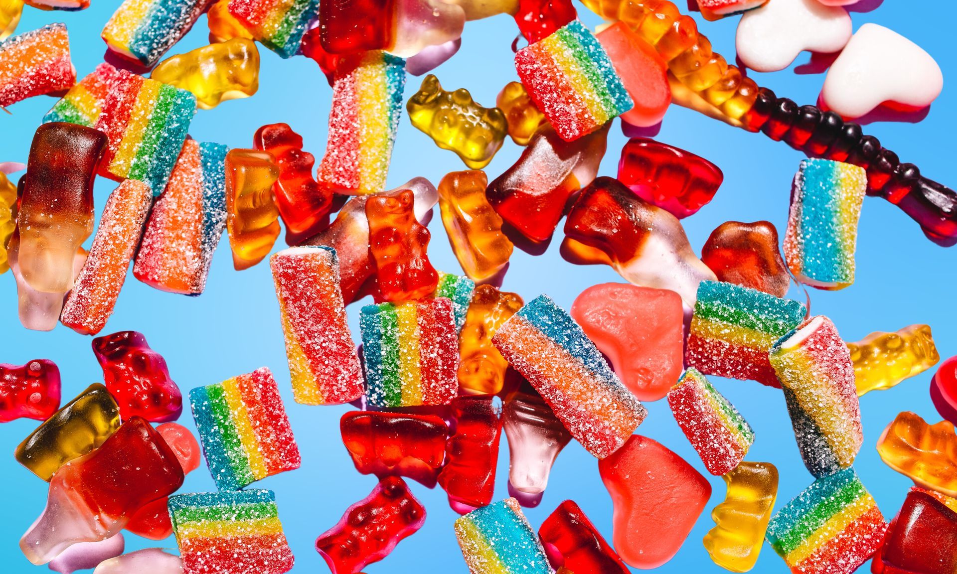 A pile of colorful gummy candies on a blue background.