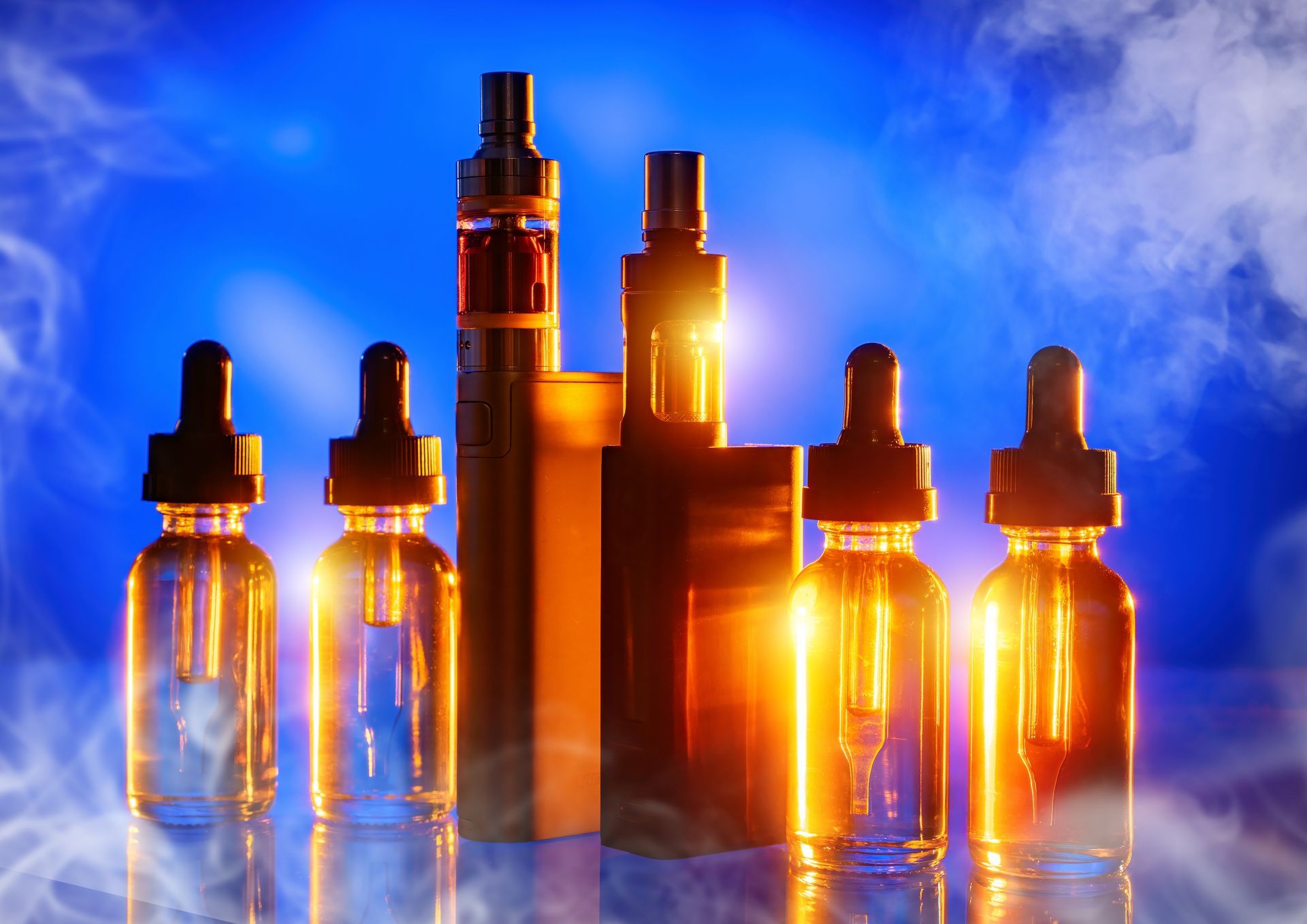 A group of electronic cigarettes and bottles of e liquid on a blue background.