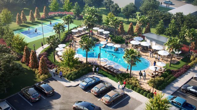 Aerial view of a community pool area with a pool, basketball court, parking lot, and people. Trees and landscaping surround the features.