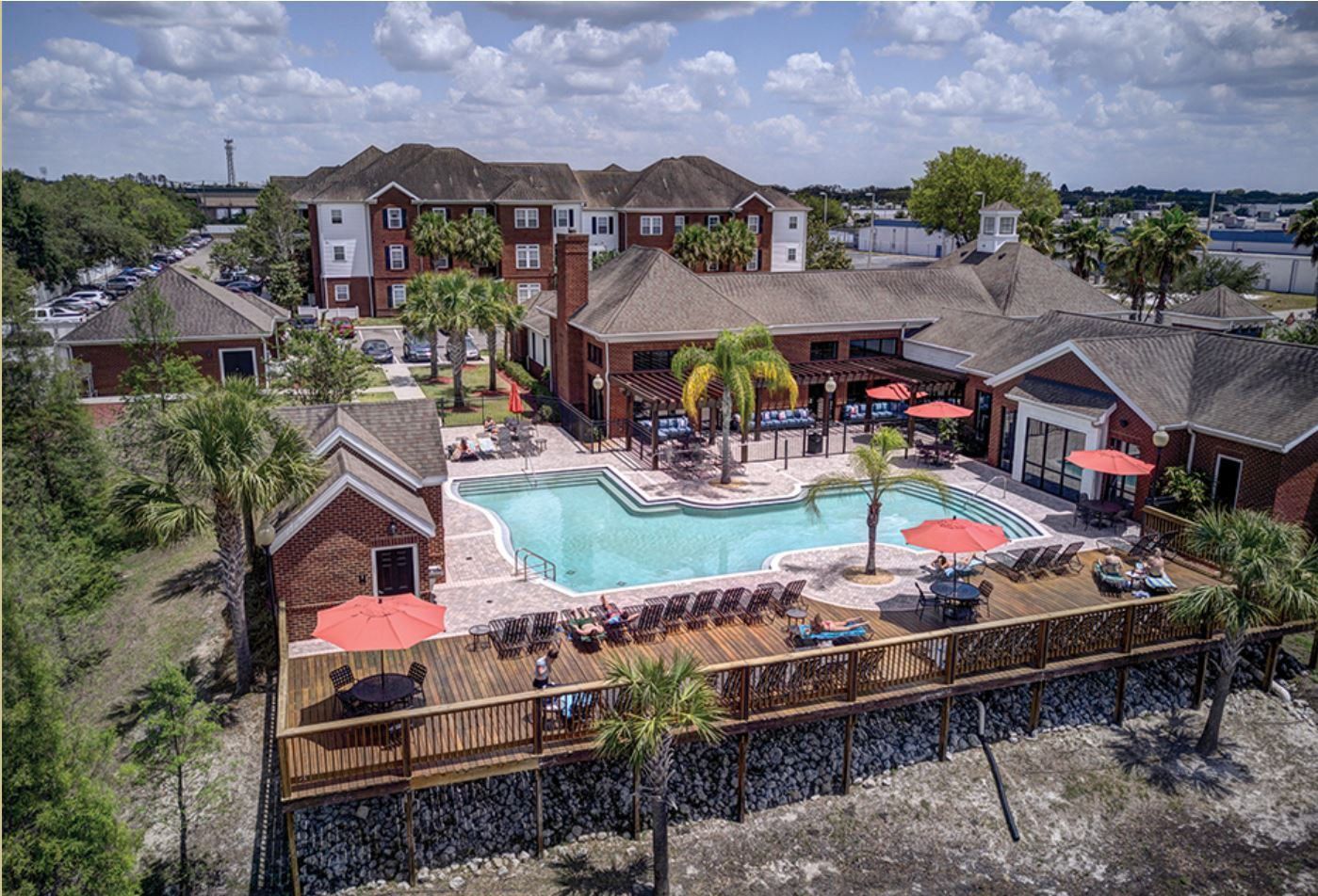 An aerial view of a large swimming pool surrounded by buildings and palm trees