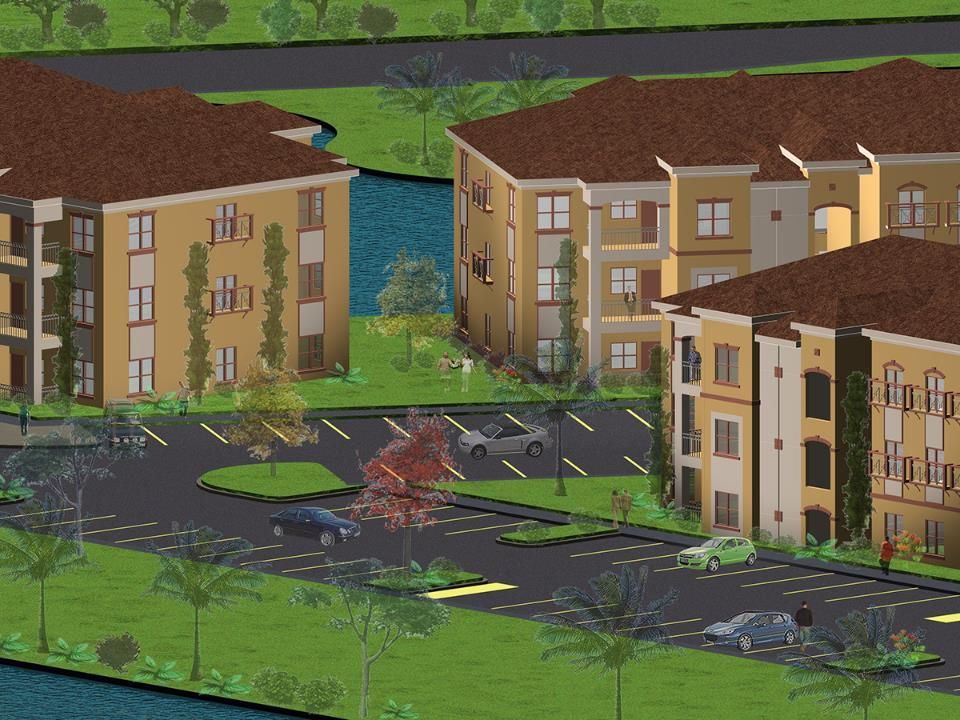 Apartment complex with tan buildings and brown tile roofs, with a parking lot and water in the foreground.