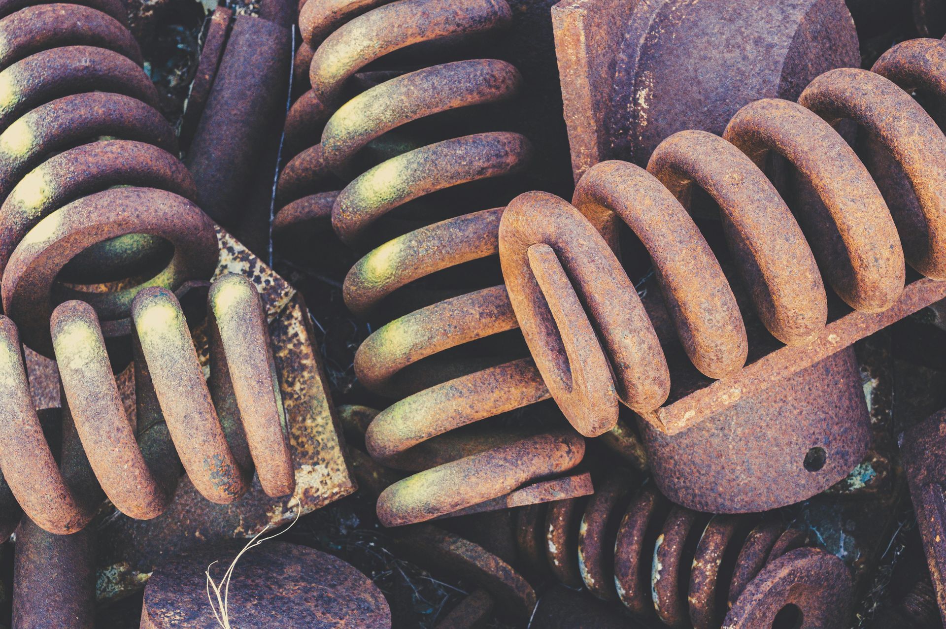 A close-up view of several thick, rusted metal coil springs piled together in a heap.