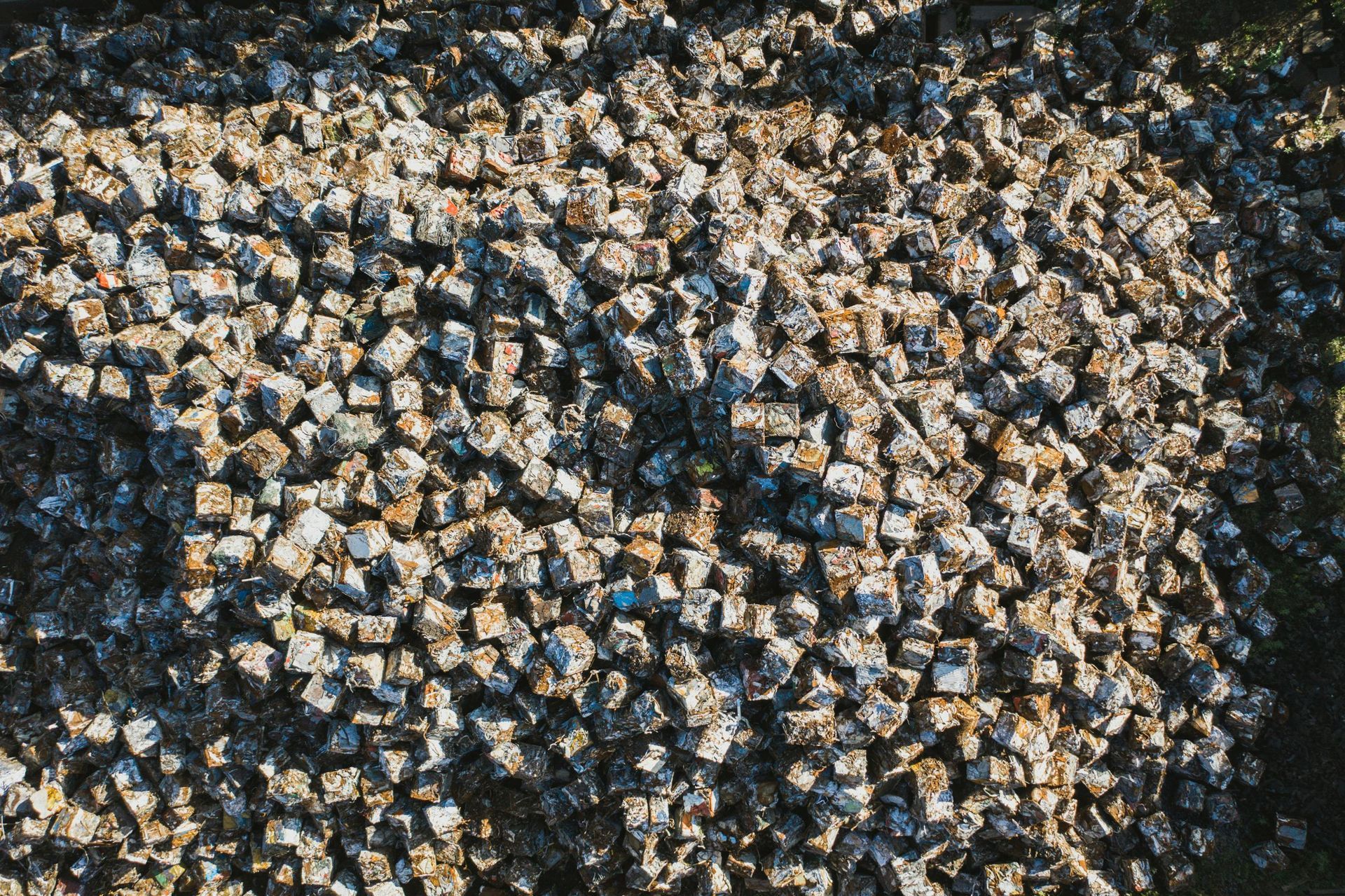 A large pile of small, weathered, grey and beige square stone blocks or pavers scattered together.