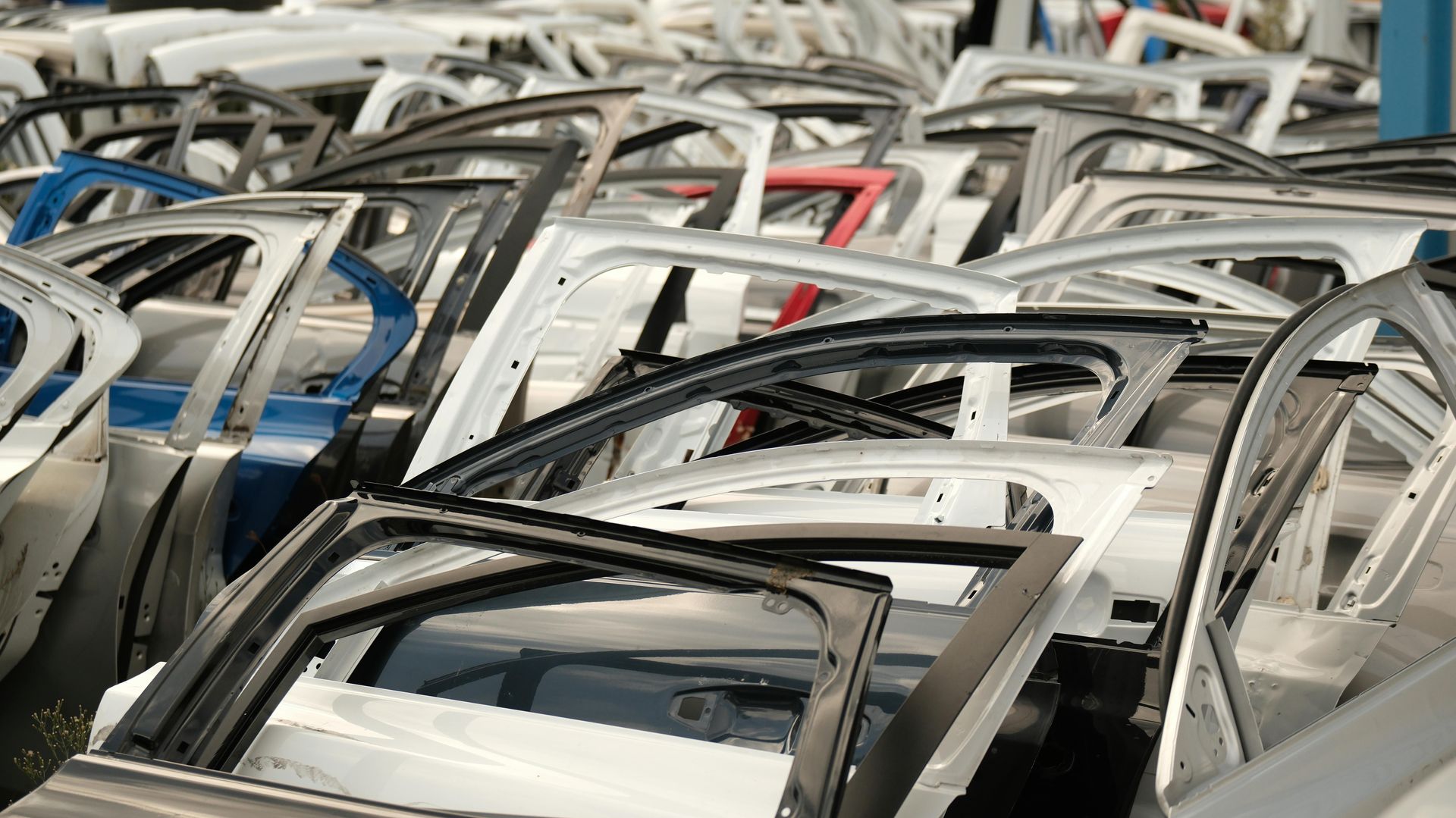 A large collection of various salvaged car doors stacked in an organized industrial salvage yard.