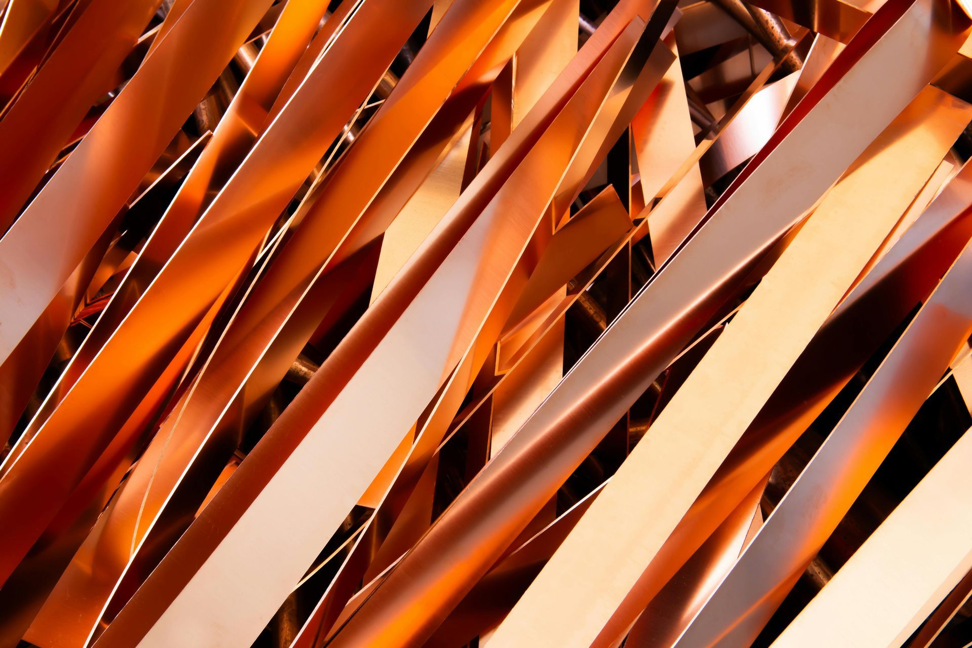 A close-up view of overlapping, thin strips of shiny, bright copper metal.