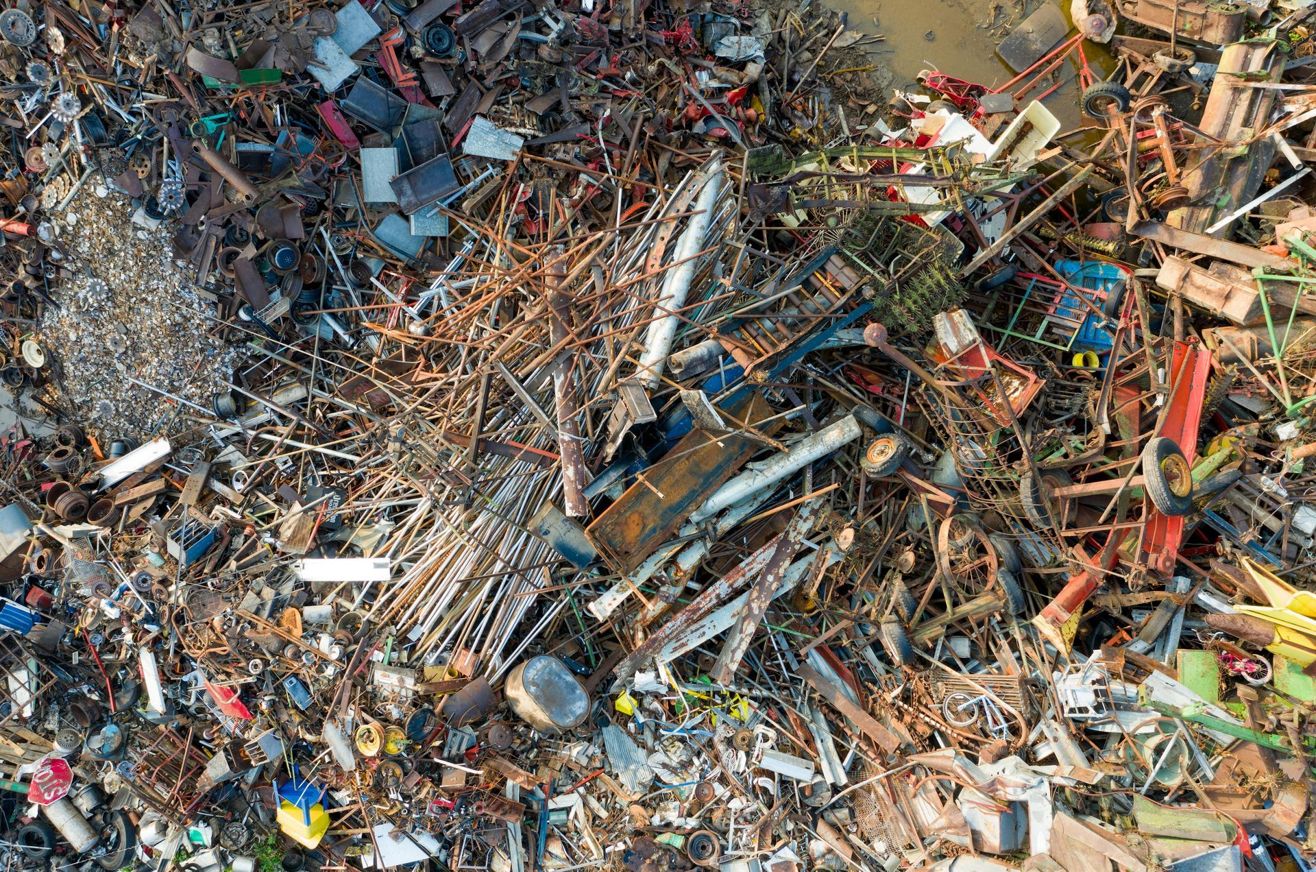 An aerial view of a junkyard filled with piles of scrap metal, debris, and discarded machinery.