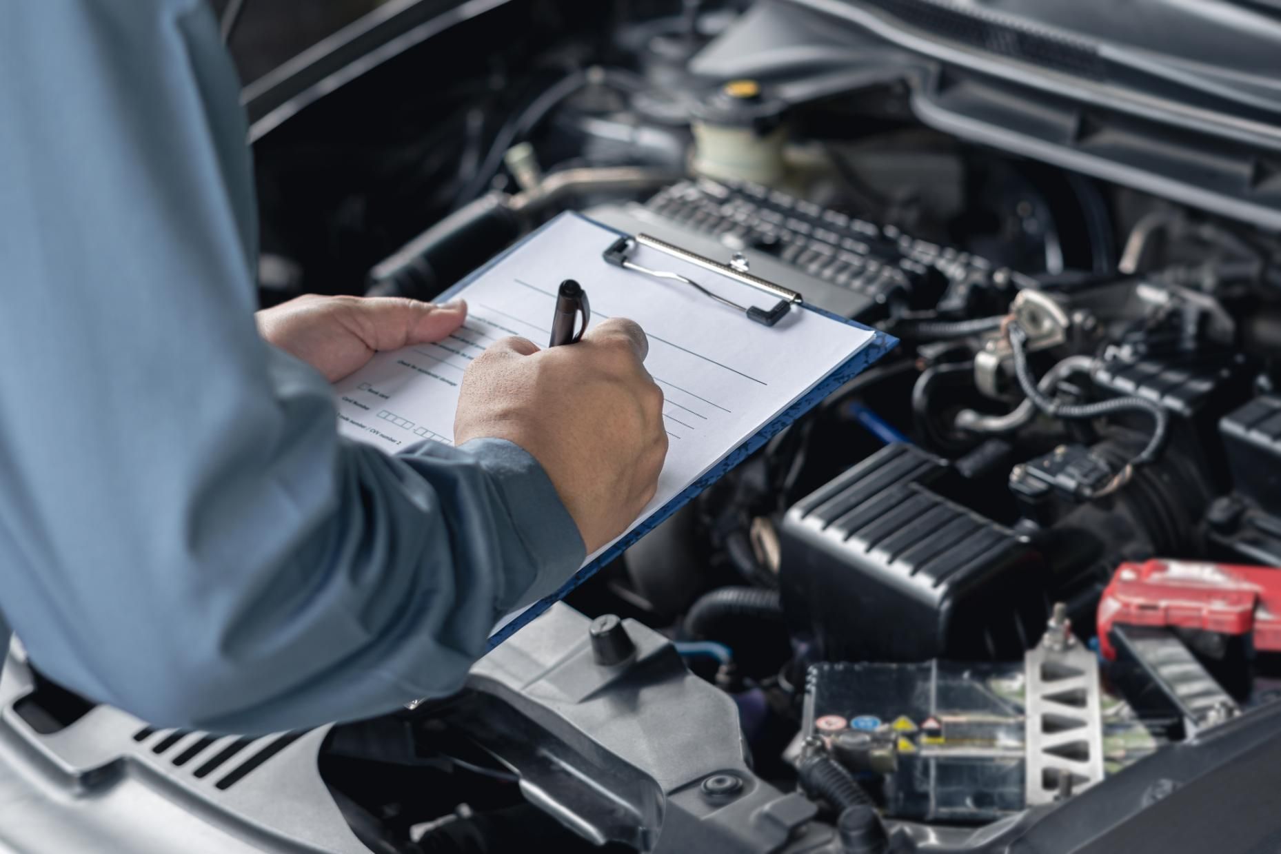 Mechanic Inspecting Car Engine Writing on Clipboard— Level Up Automotive In Unanderra, NSW