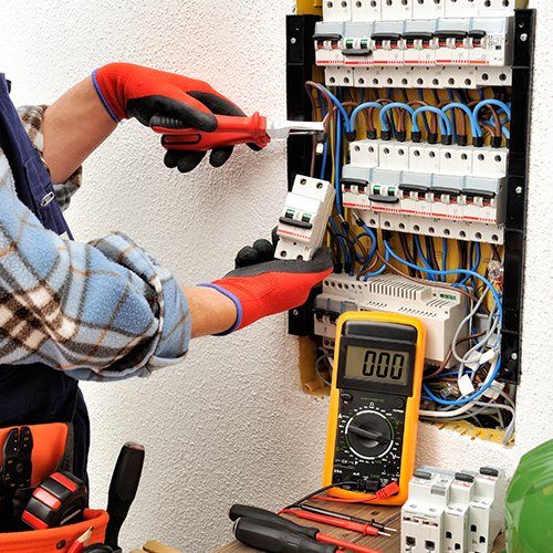 Electric Water Heaters  — Man Fixing and Testing Wires in Hockessin, DE