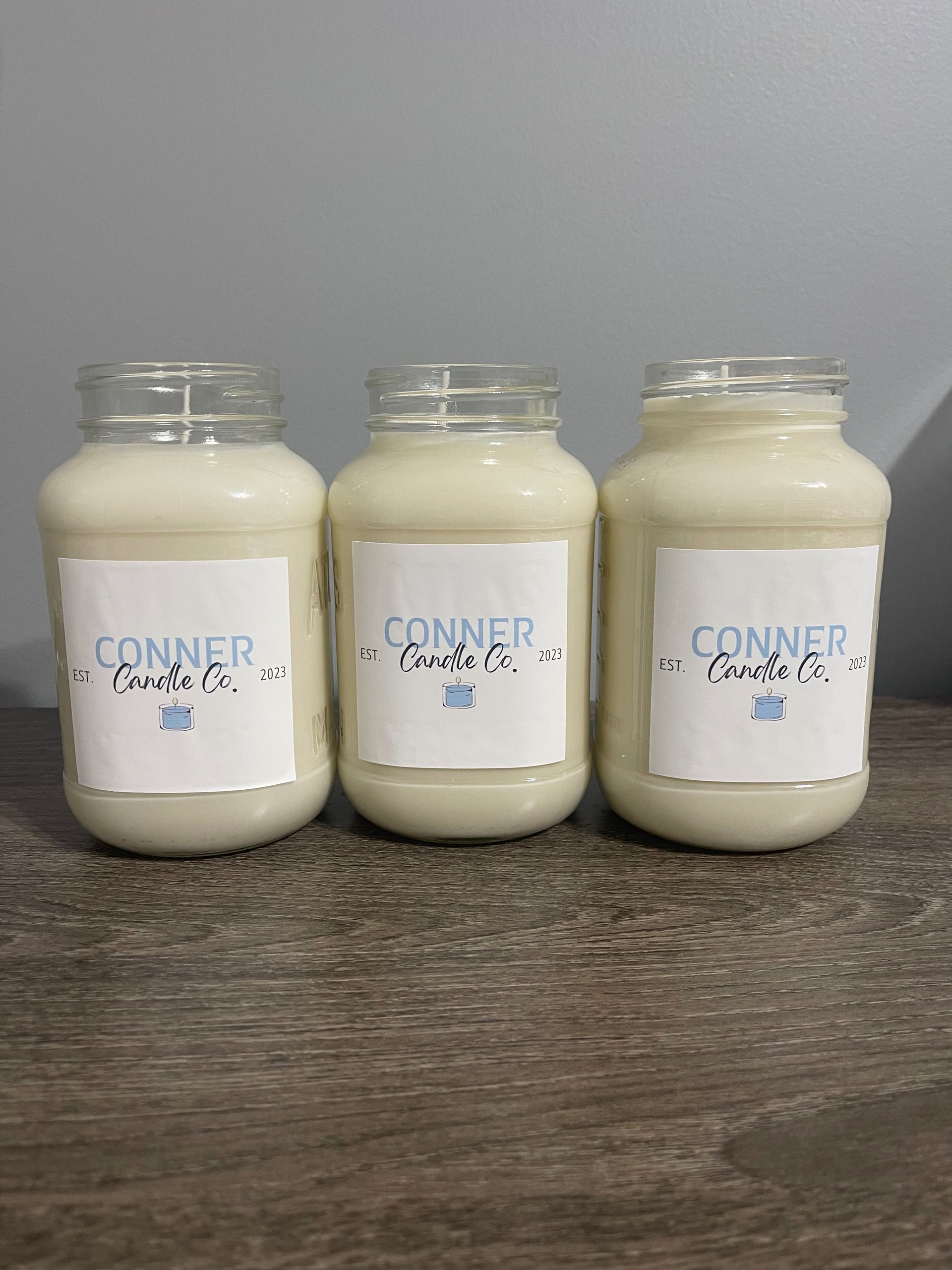 Three glass jars filled with light-colored liquid on a wooden surface, each with a labeled paper square.