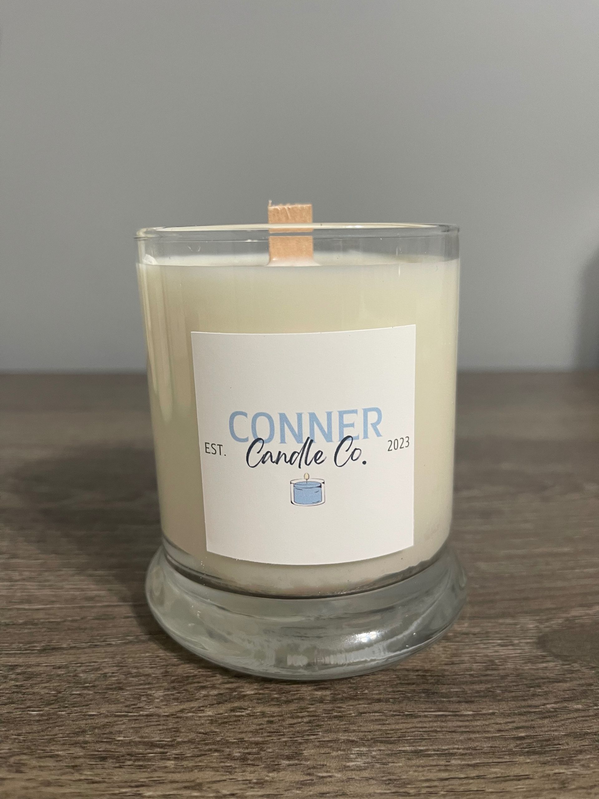 Candle in a clear glass jar with a wooden wick, labeled 
