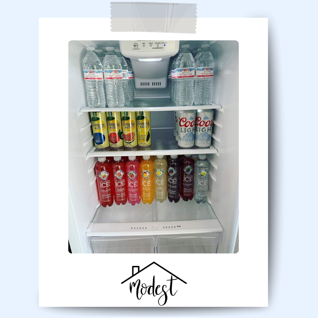 Refrigerator stocked with water bottles and colorful beverages.