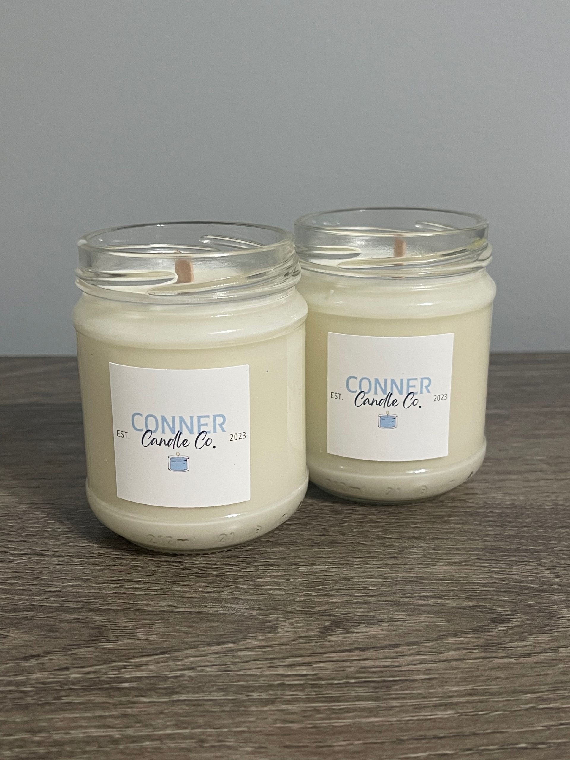 Two white candles in glass jars, labeled 