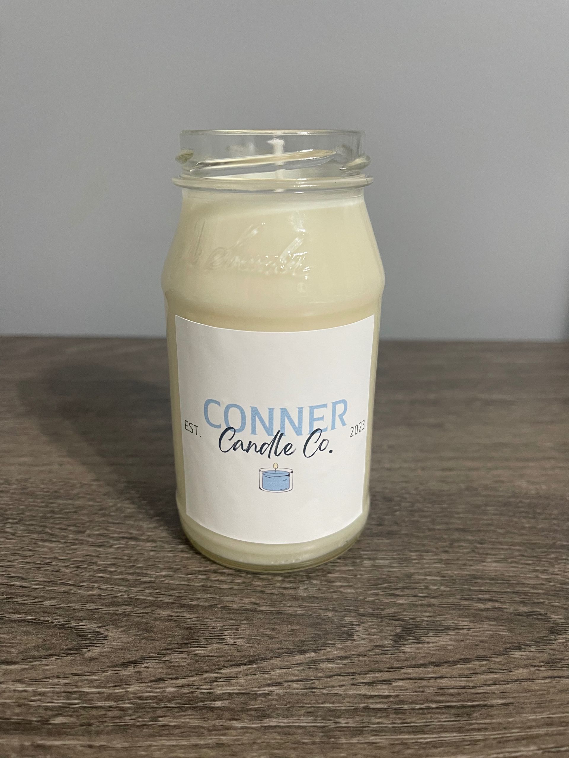 White candle in a jar with a label that says 