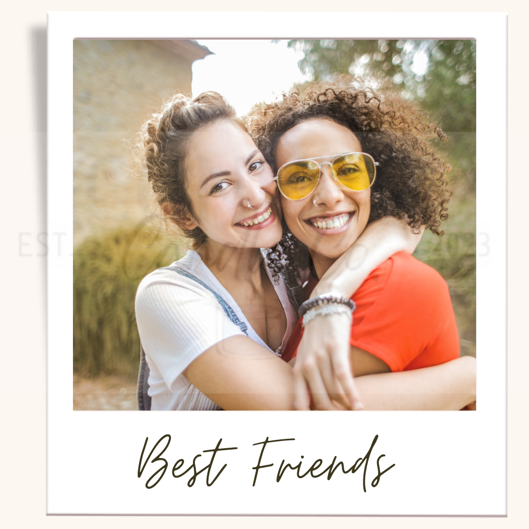 Two smiling women hugging outdoors. One wears yellow sunglasses and an orange shirt.