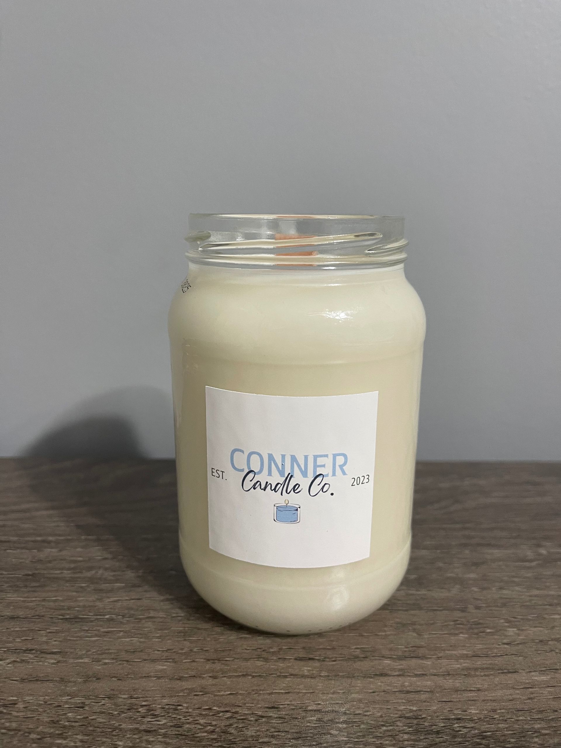 Glass jar with a white label, filled with a white substance, sitting on a wooden surface.
