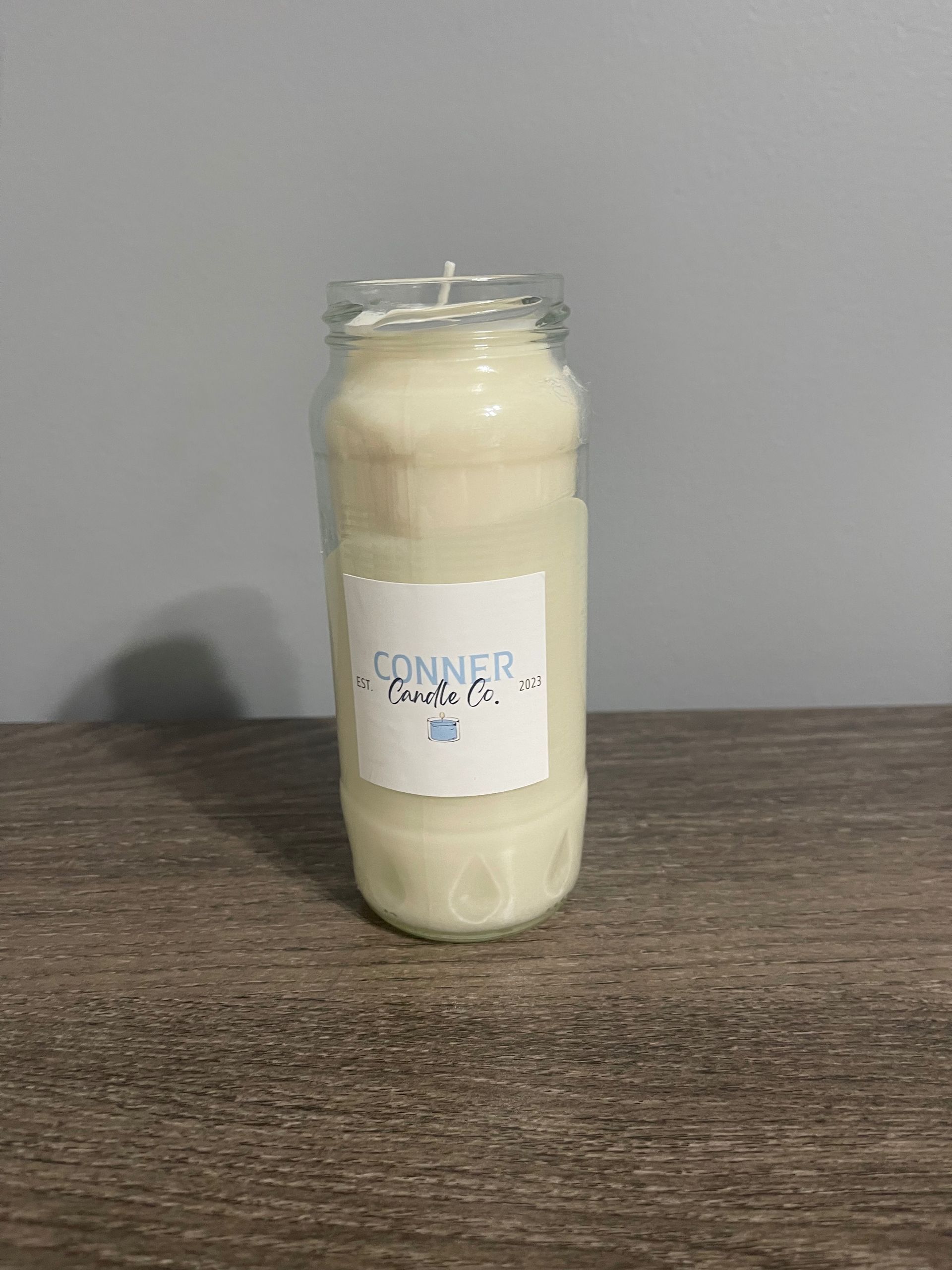 White candle in a glass jar, with a label reading 
