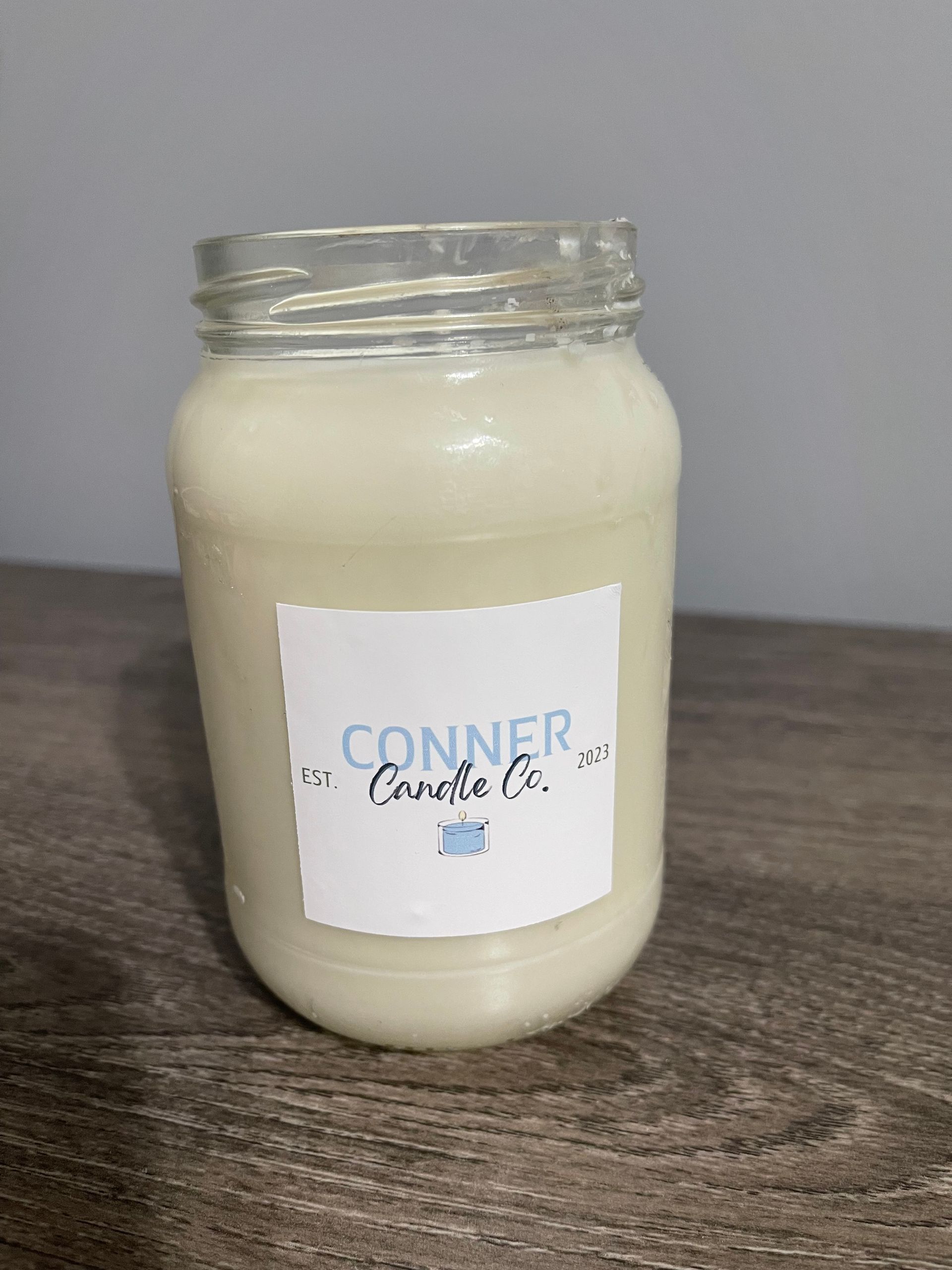 Cream-colored candle in a mason jar with a label that says 