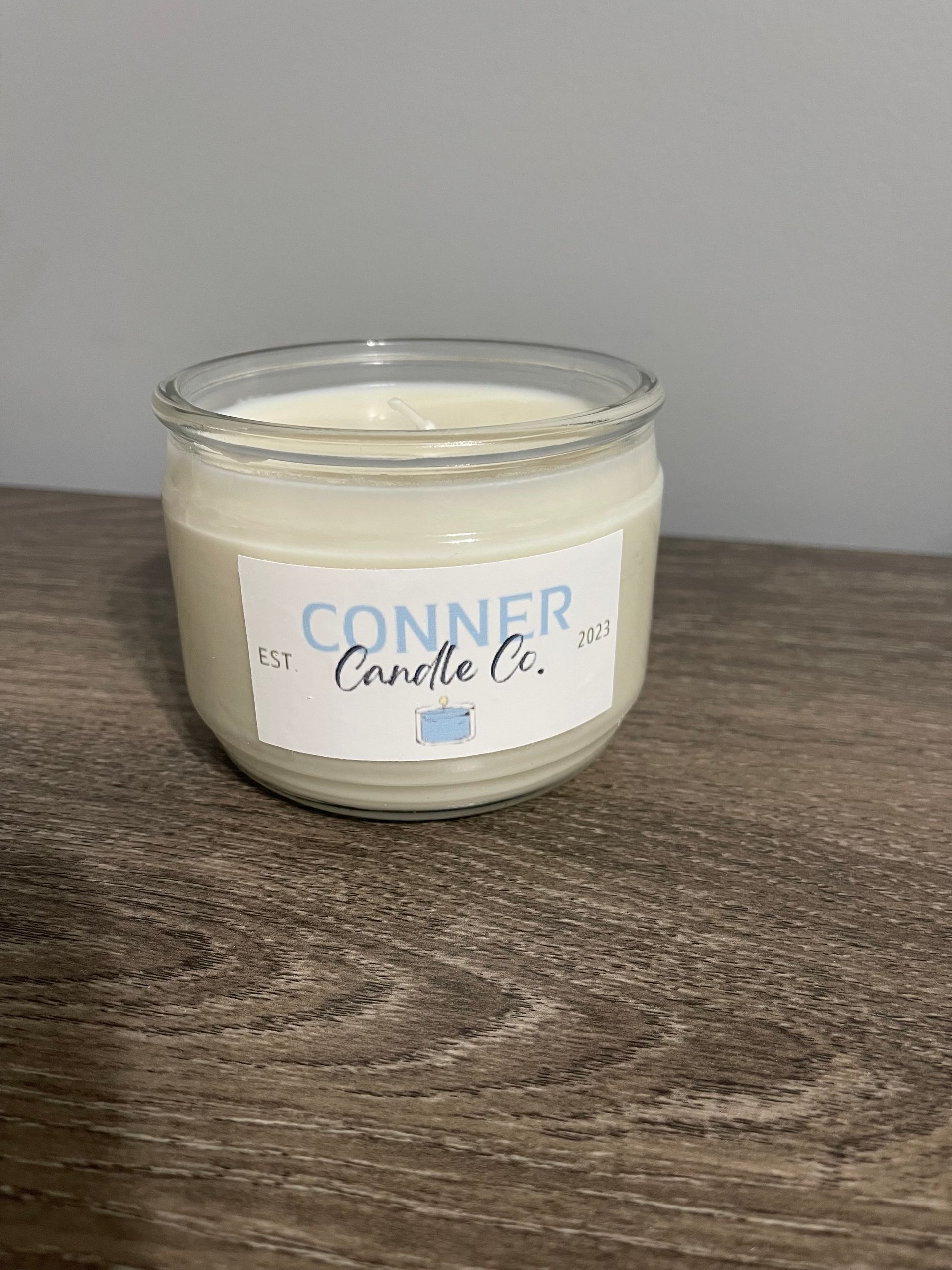 White candle in a clear glass jar with a label that says 