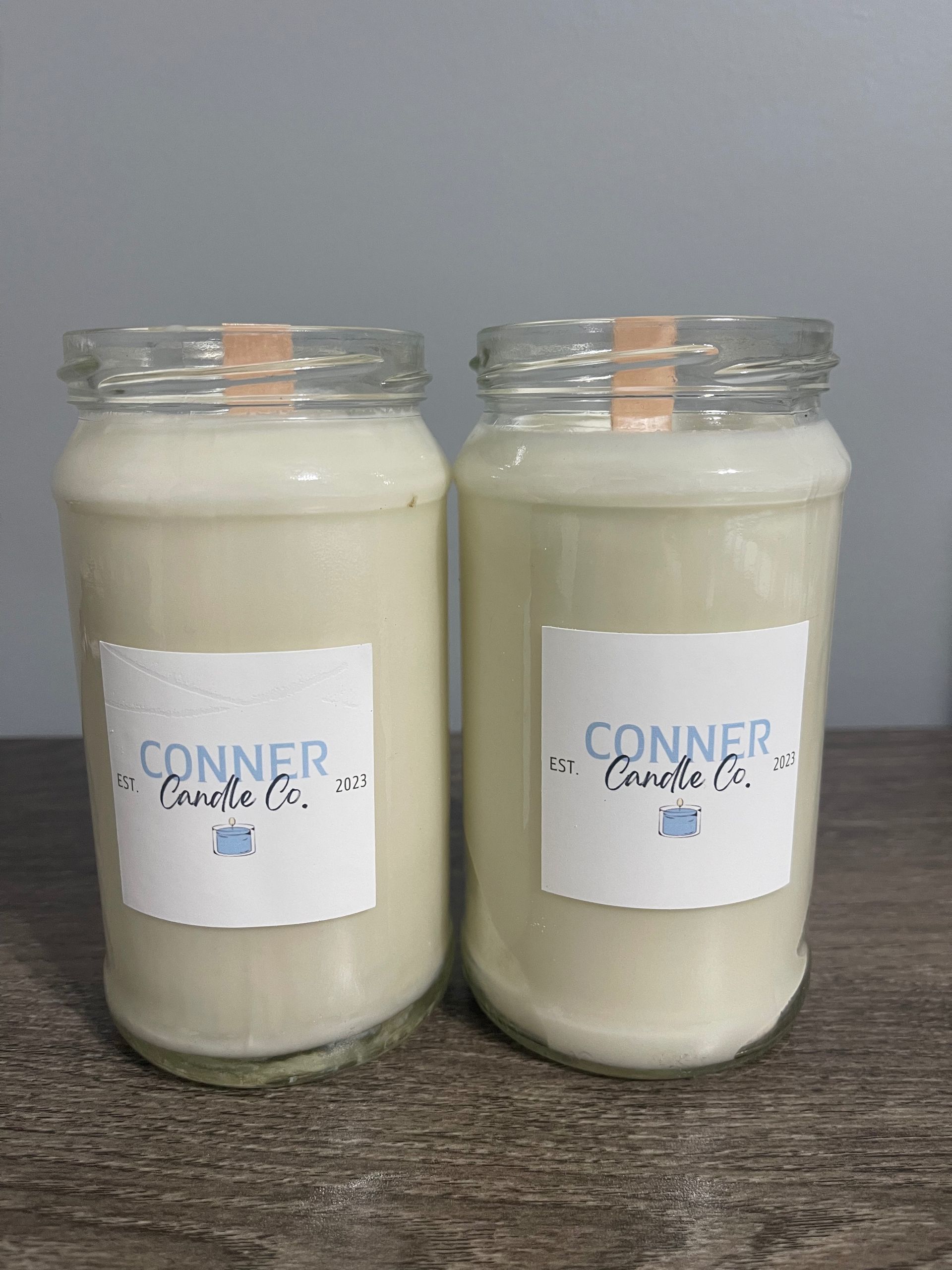Two white candles in glass jars, labeled "Conner Candle Co."