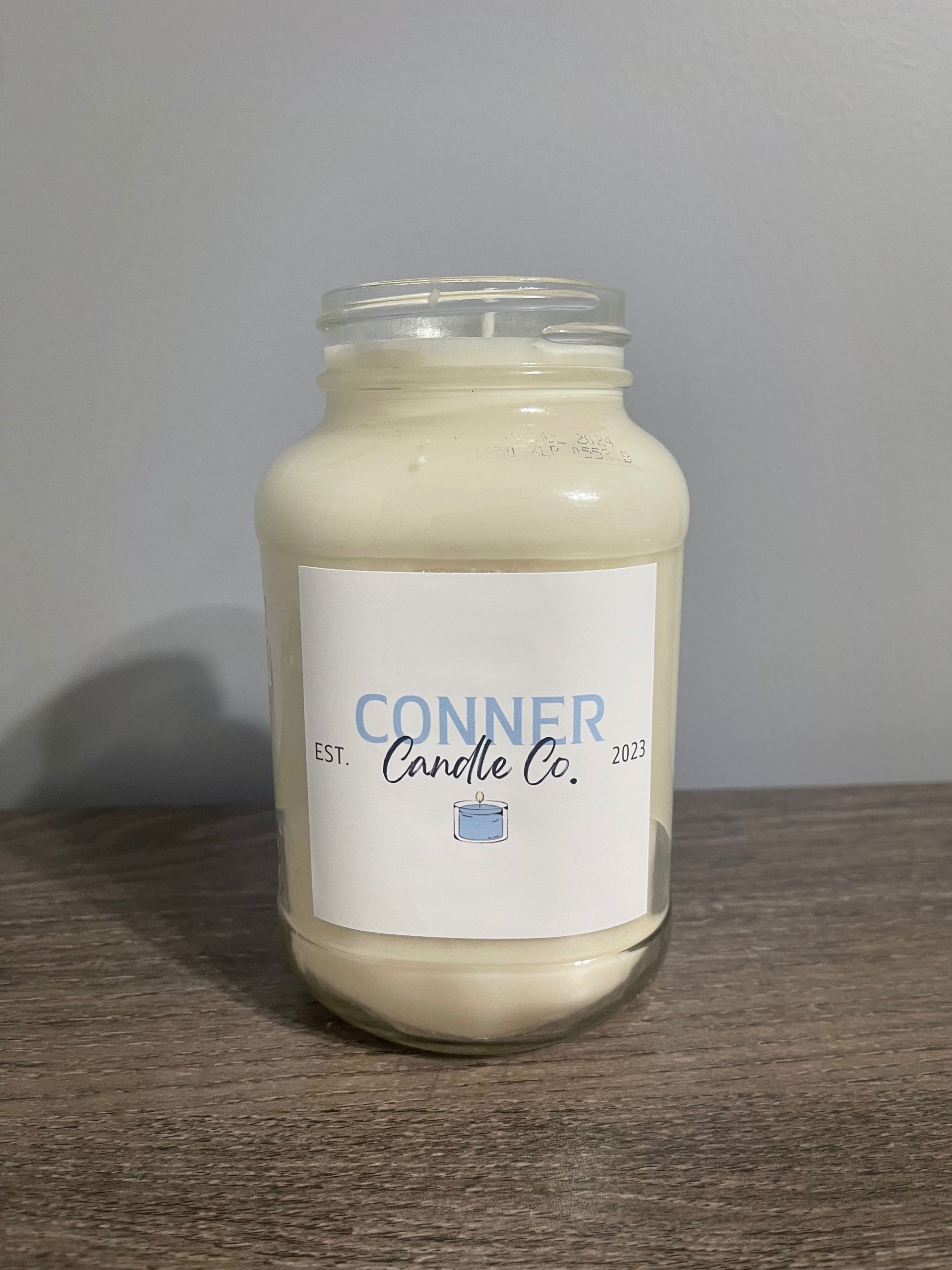 A glass jar candle with a white label reading 