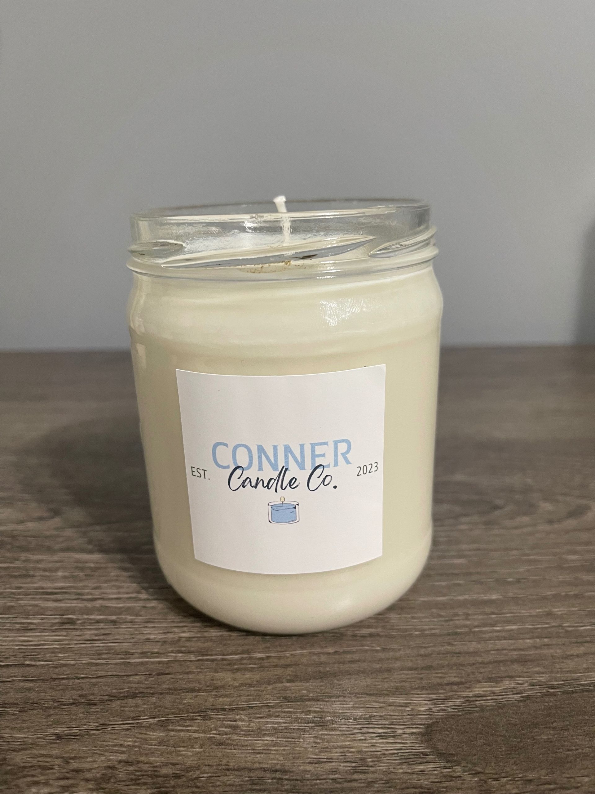 White candle in a mason jar with a label that says 
