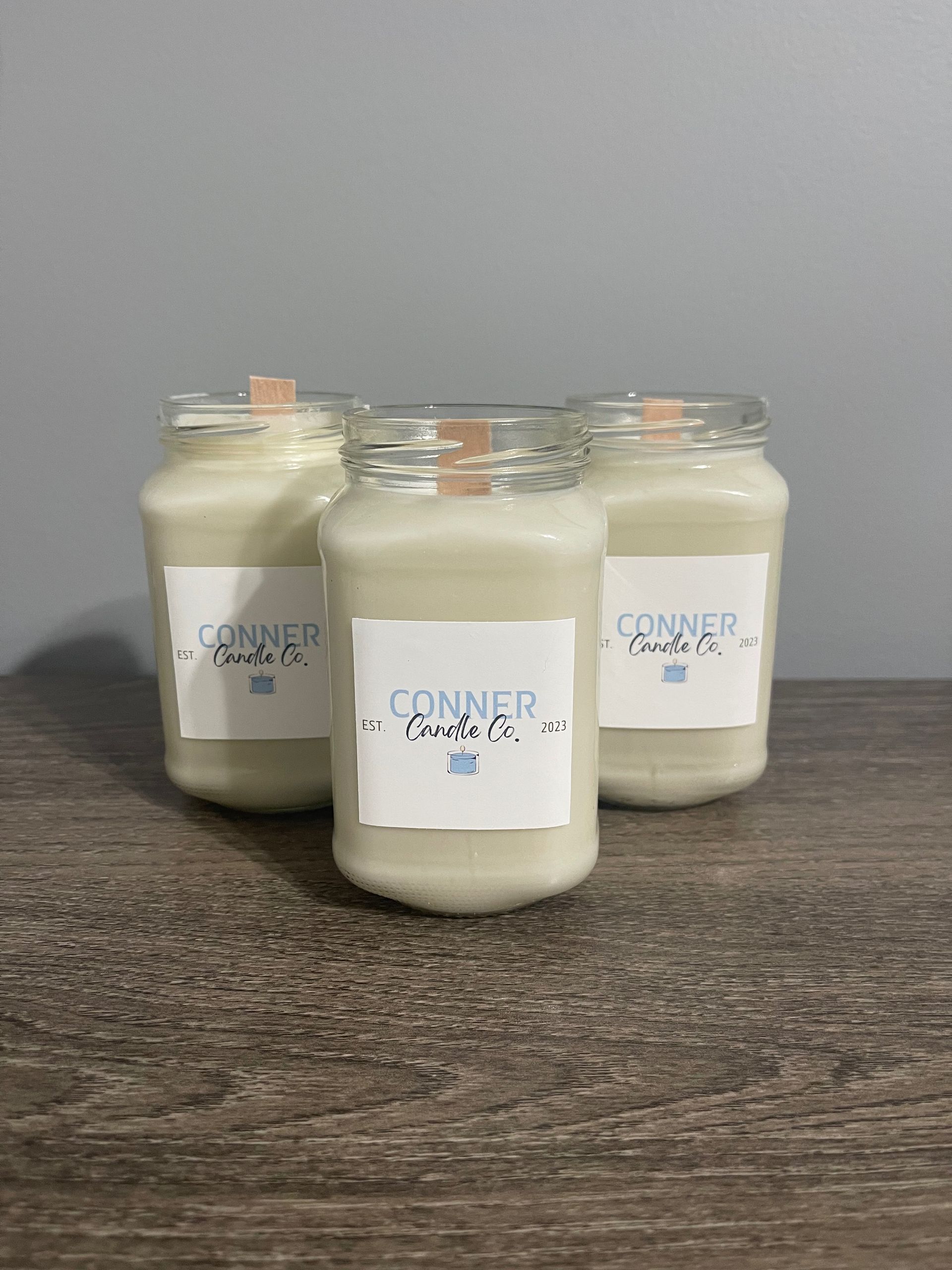 Three cream-colored jar candles with labels that read 