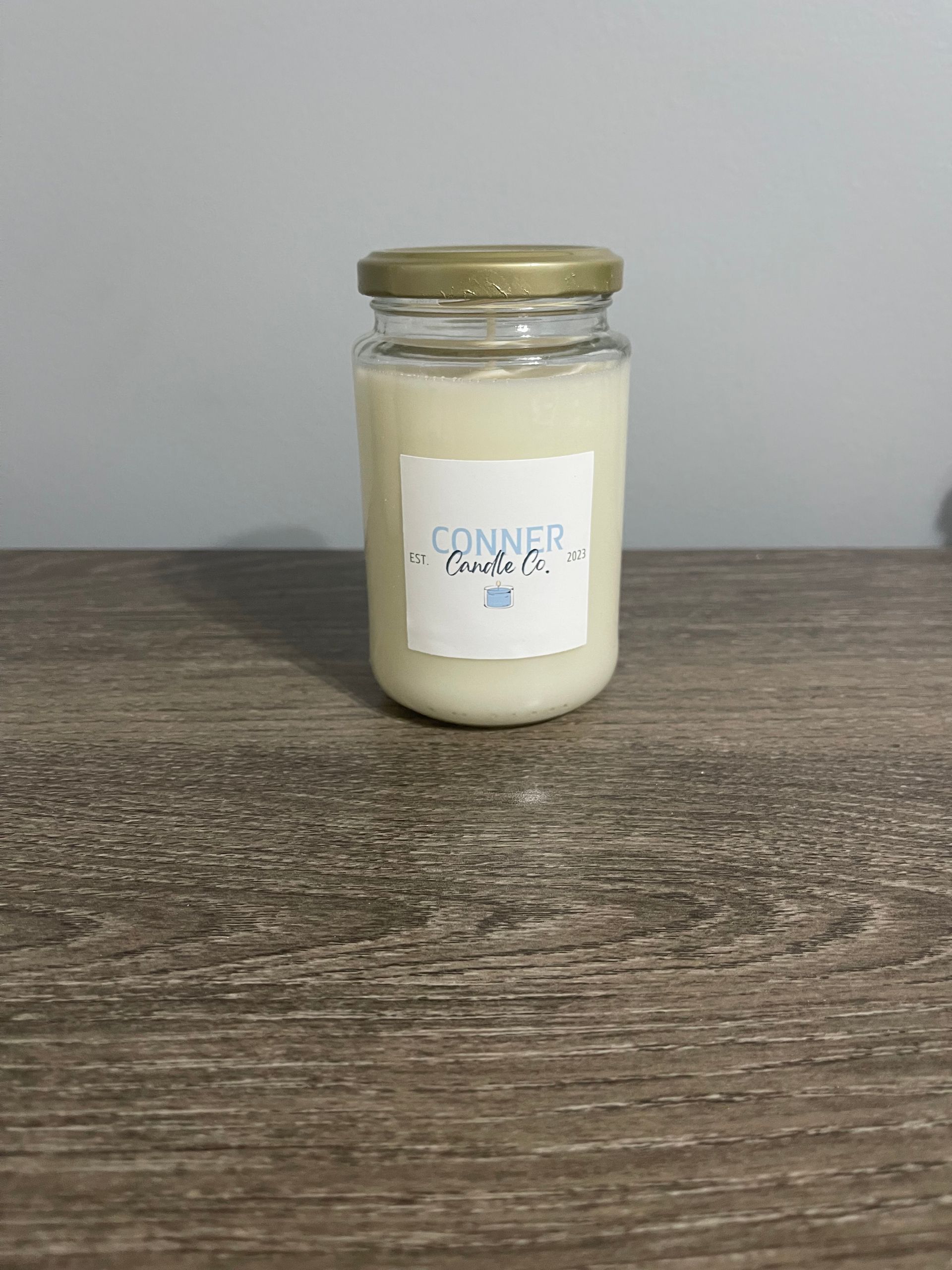 A candle in a glass jar, labeled 