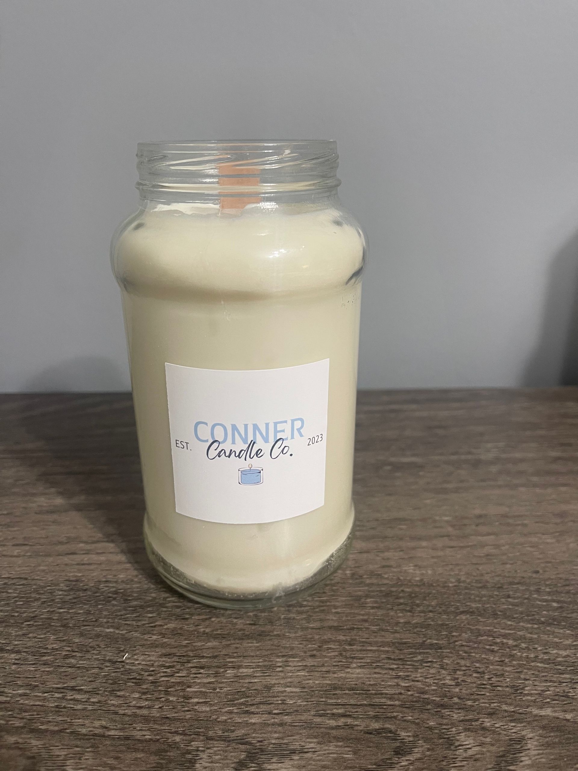 White candle in a clear glass jar with a label that reads 
