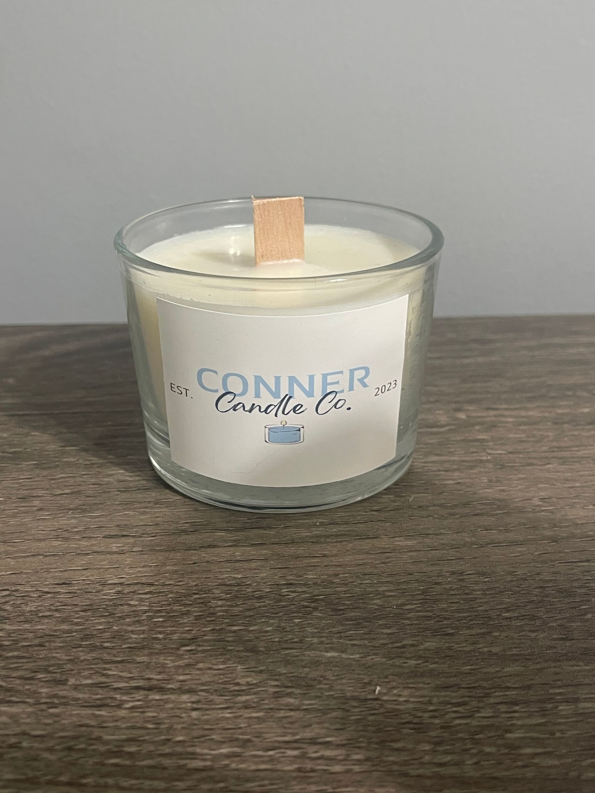 Candle in a clear glass jar with wooden wick, label says 