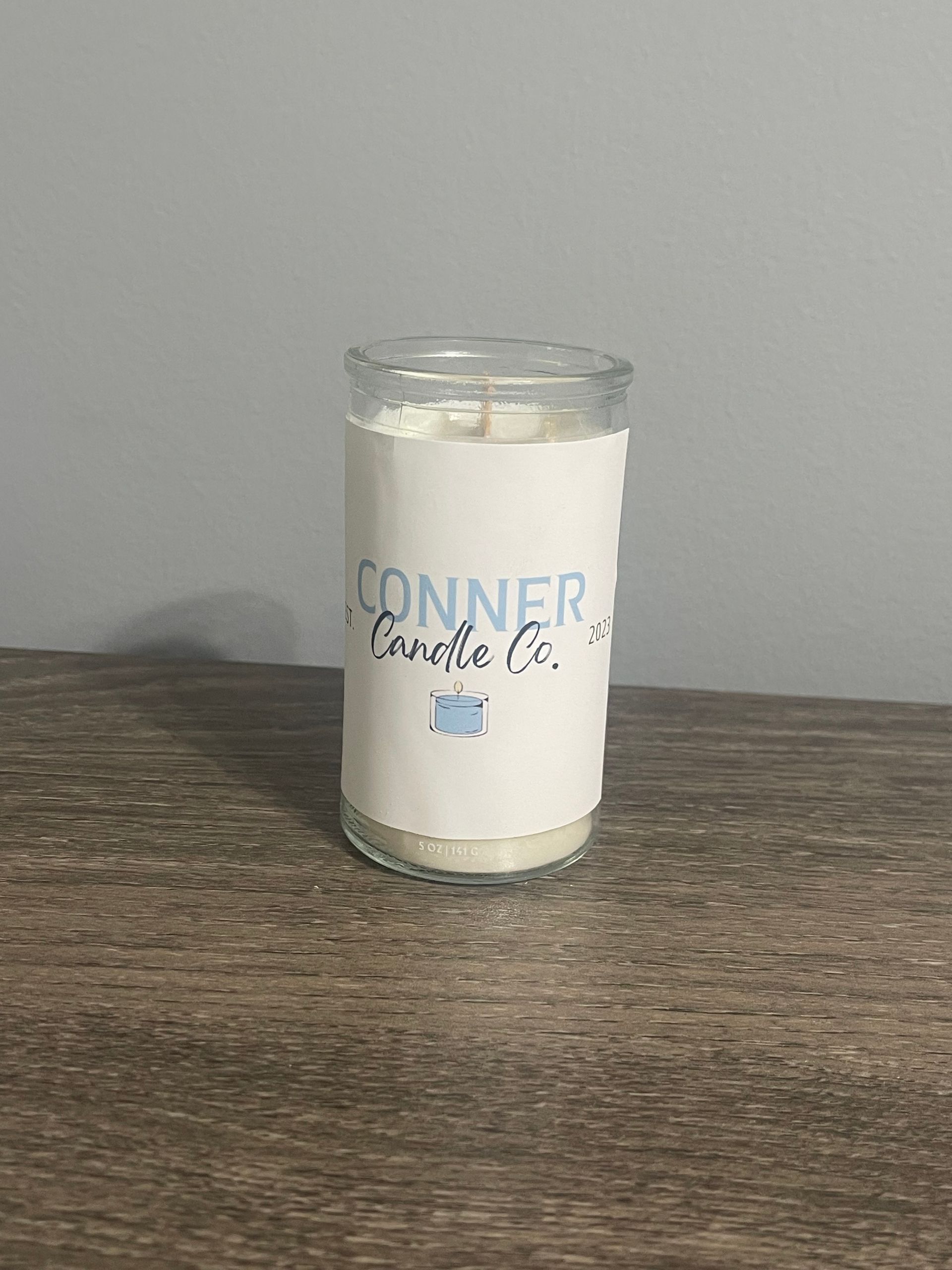 Candle in a clear glass jar with a white label that reads 